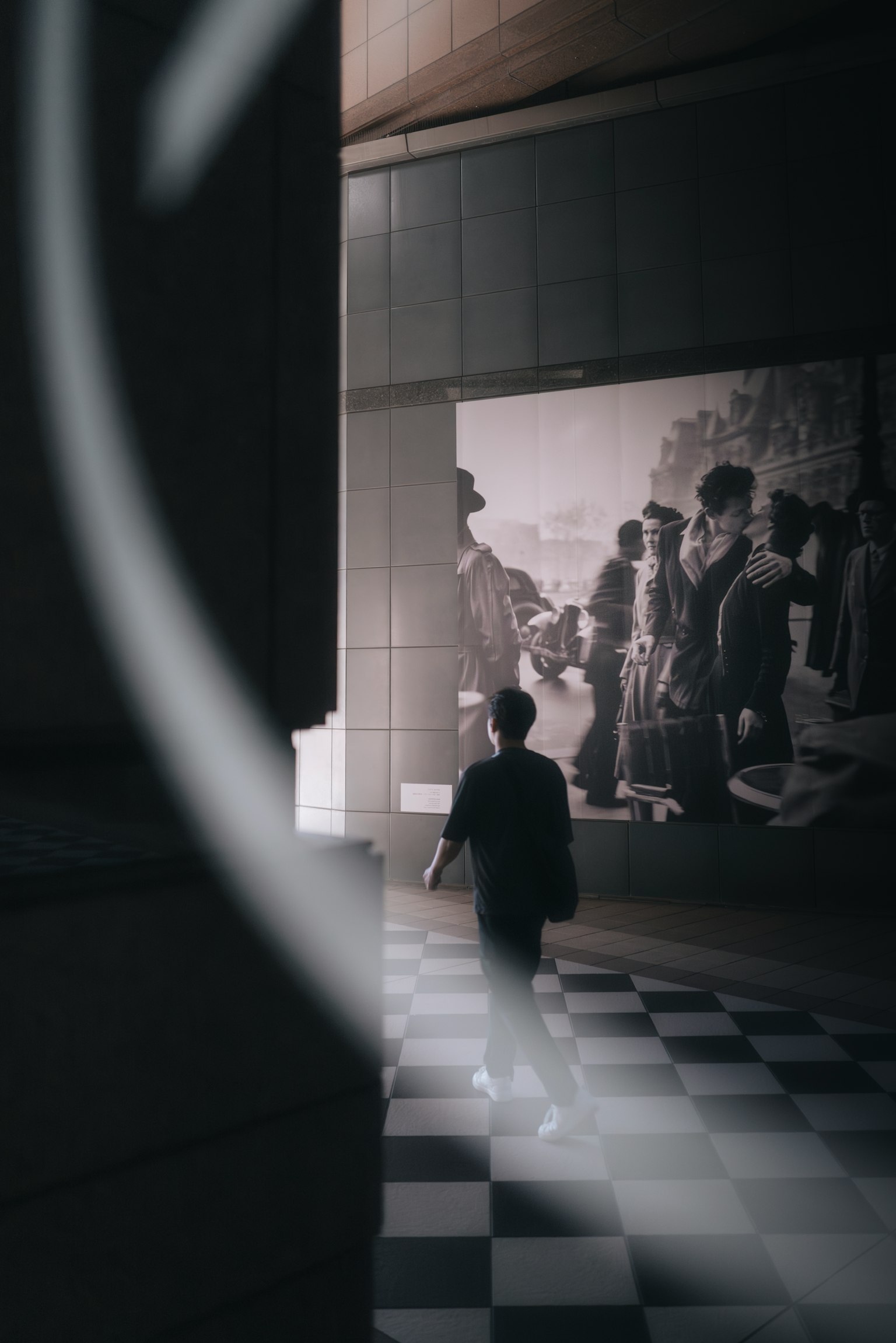 Une personne marchant sur un sol en damier avec un fond de photo historique