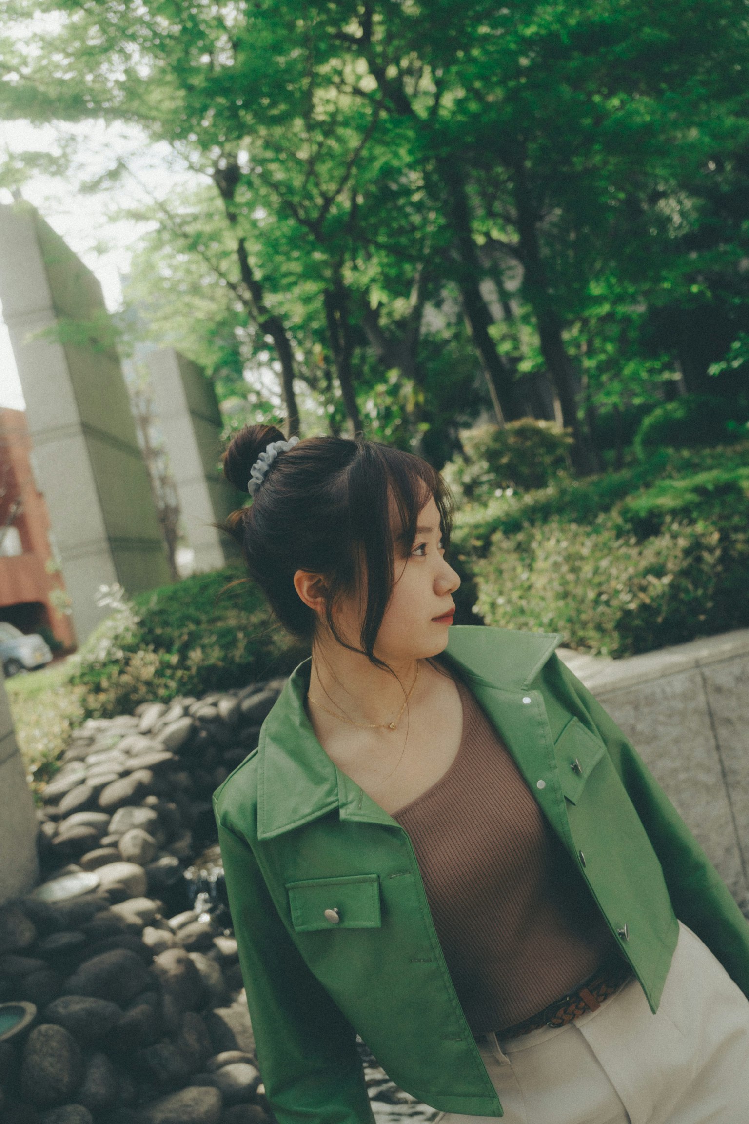 หญิงสาวในแจ็คเก็ตสีเขียวหันไปในสภาพแวดล้อมธรรมชาติ