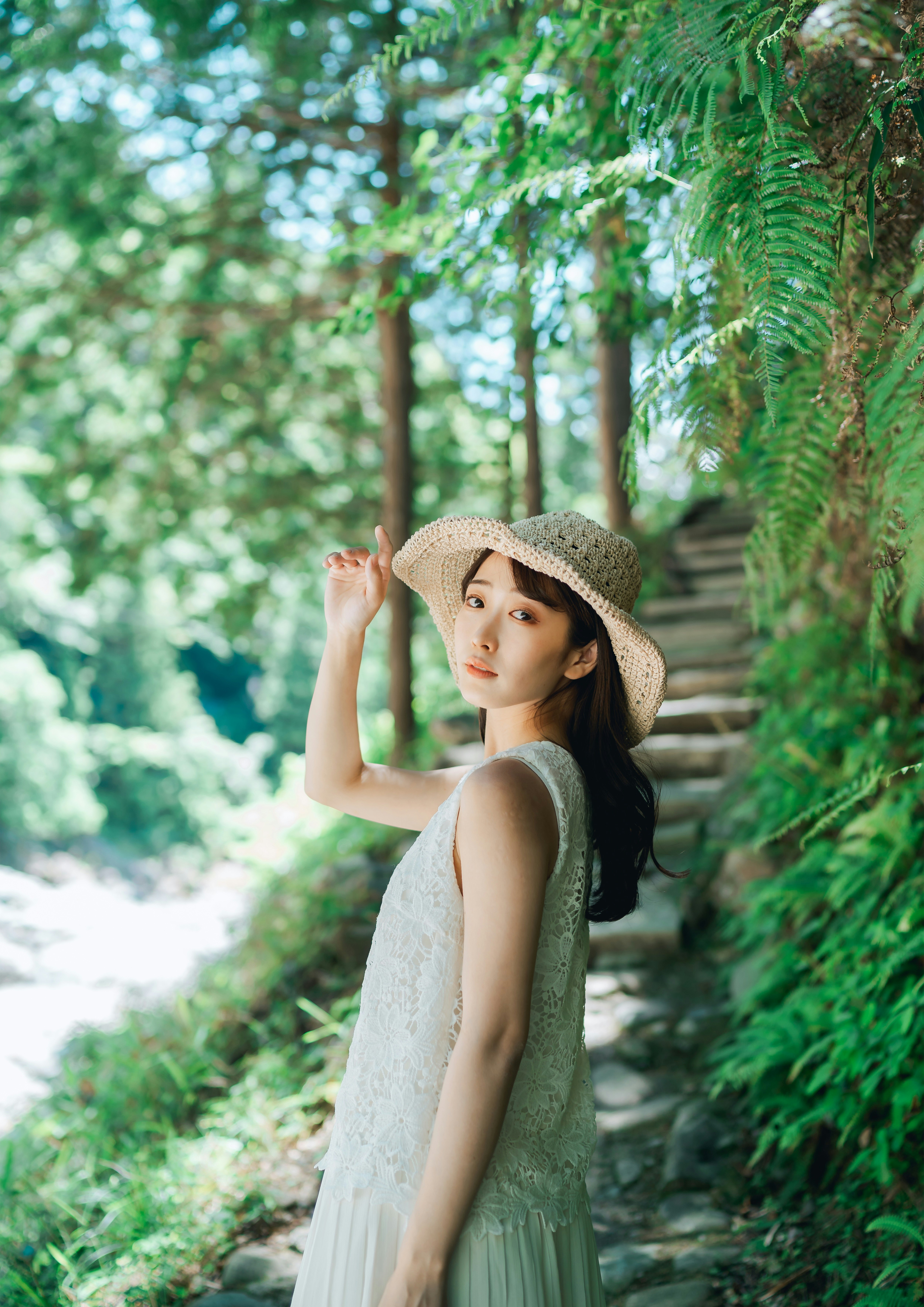 緑の小道で帽子をかぶった女性の夏の散策