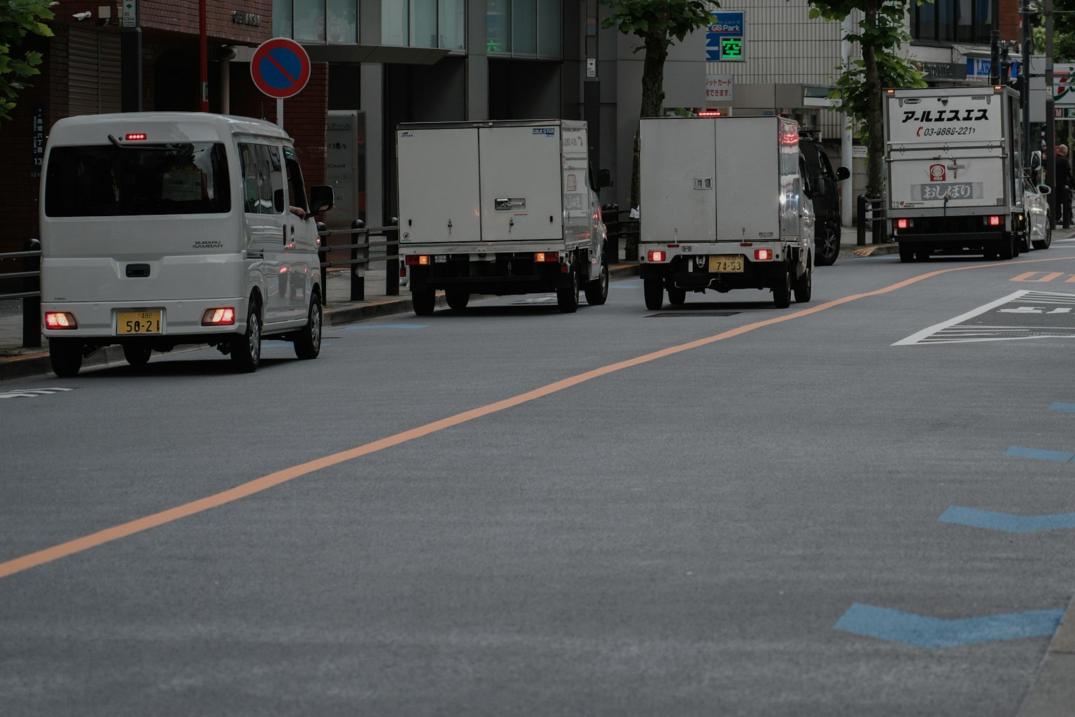 Camiones de entrega blancos circulando por una calle de Tokio