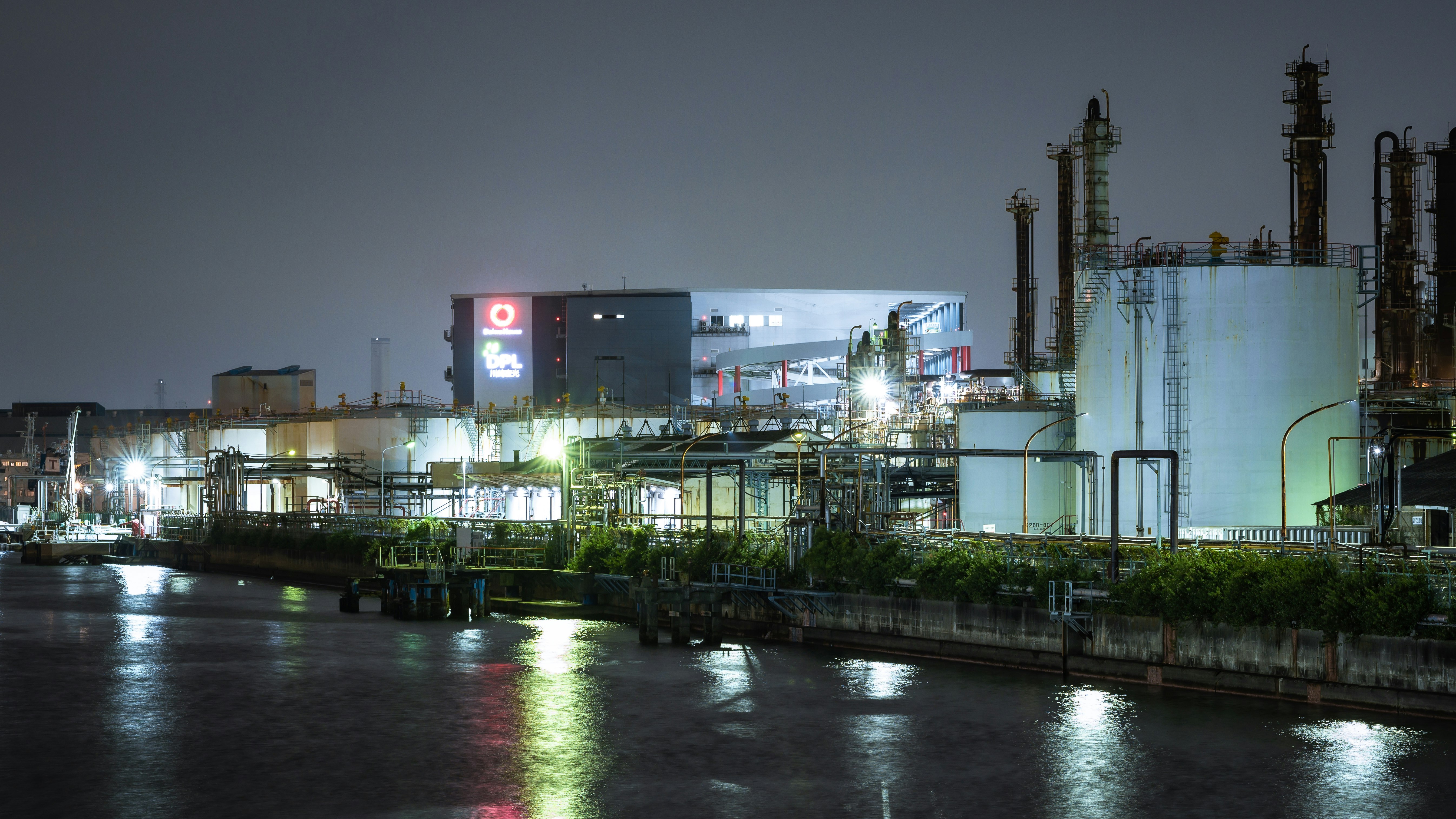 工場の夜景と照明が反射する運河沿いの風景