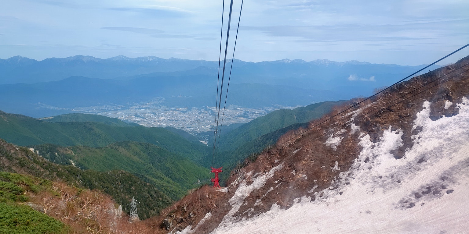 Panoramablick von einem Berg mit üppigem Grün und entfernten Städten