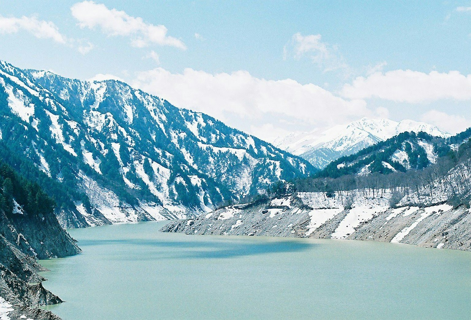 Serene lake surrounded by mountains blue sky and snow-capped peaks create a tranquil scene