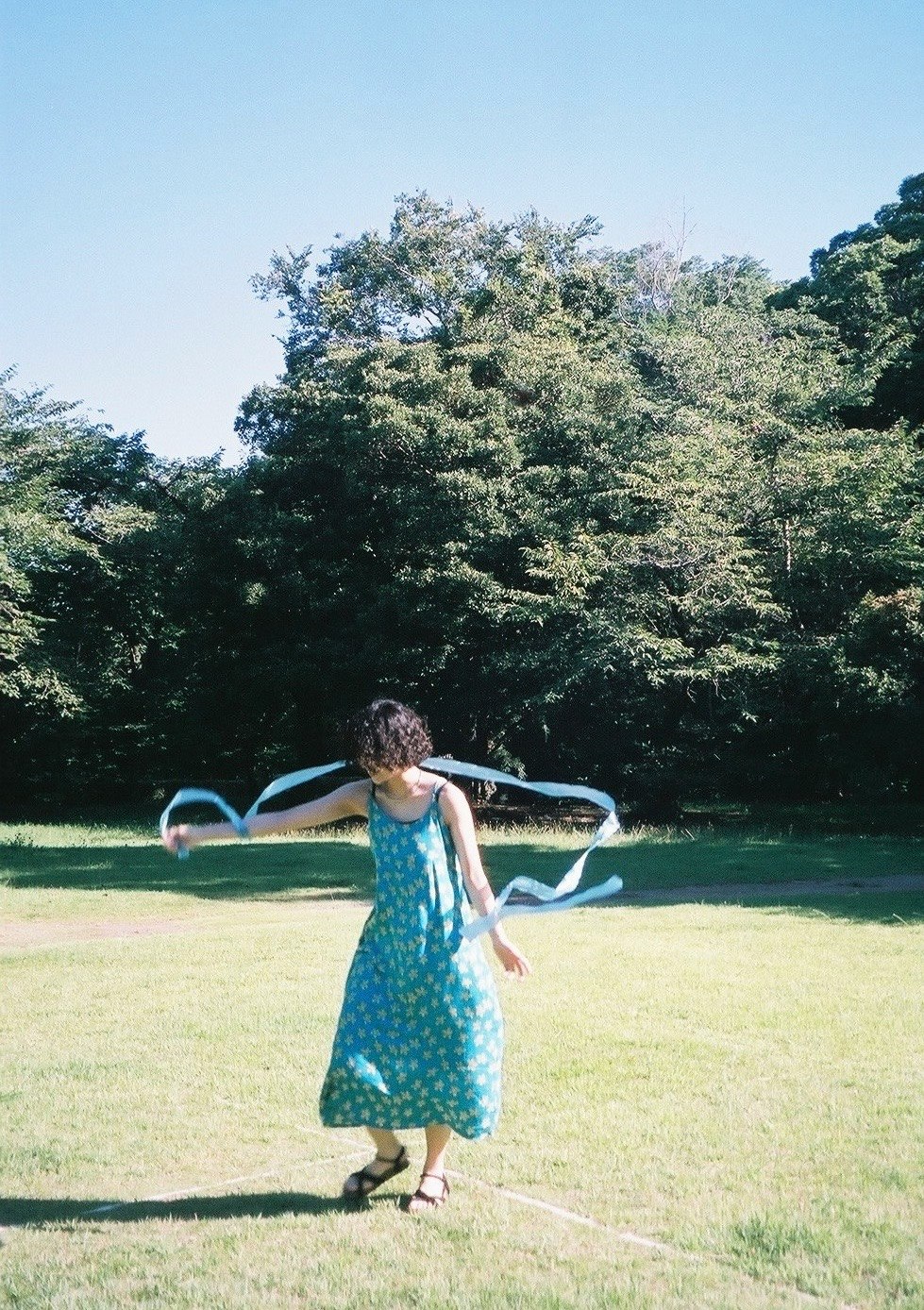 woman with arms outstretched on a grassy park lawn