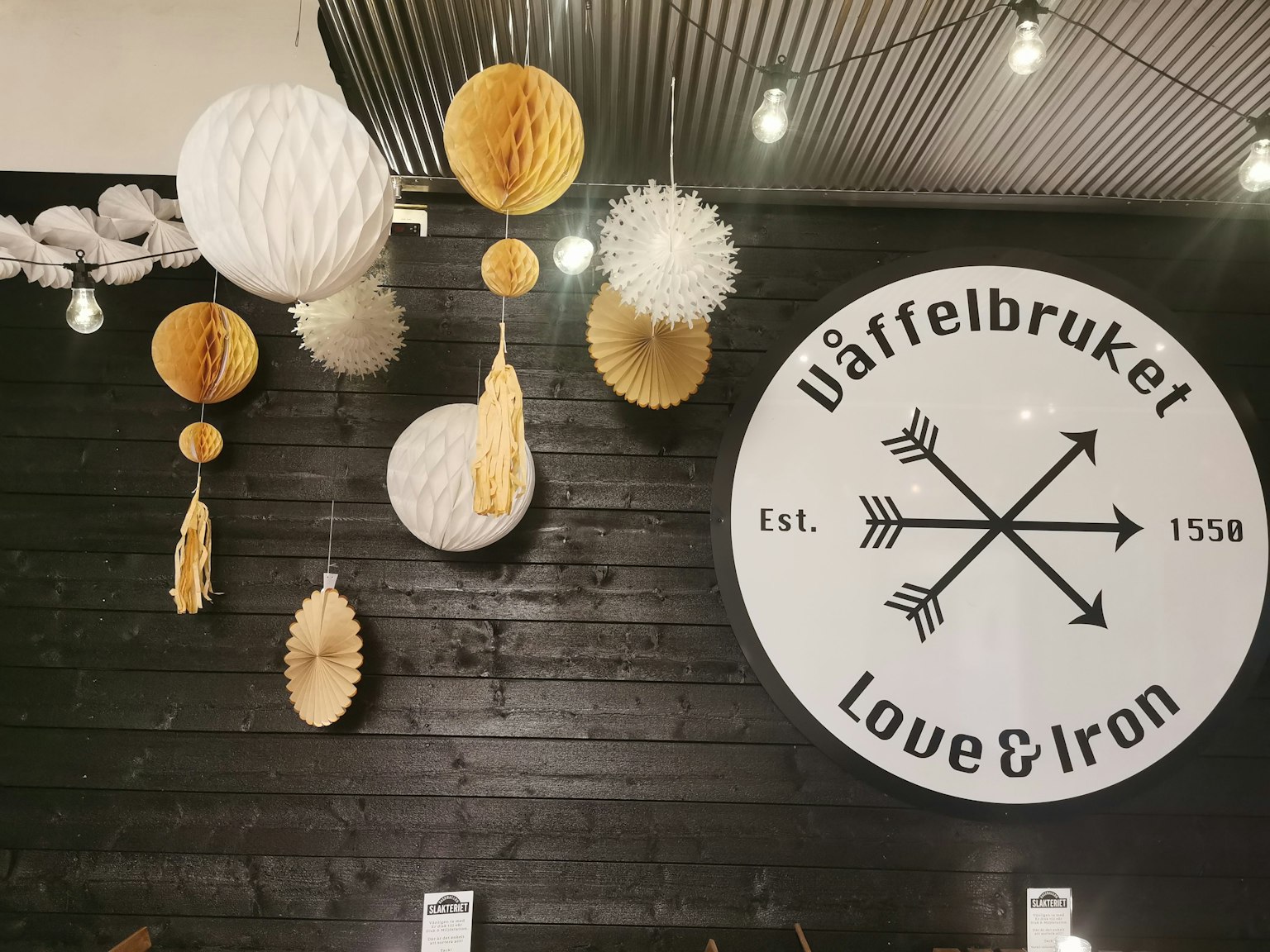 Decorazioni bianche e gialle appese a un muro nero con il segno Wafflebruket