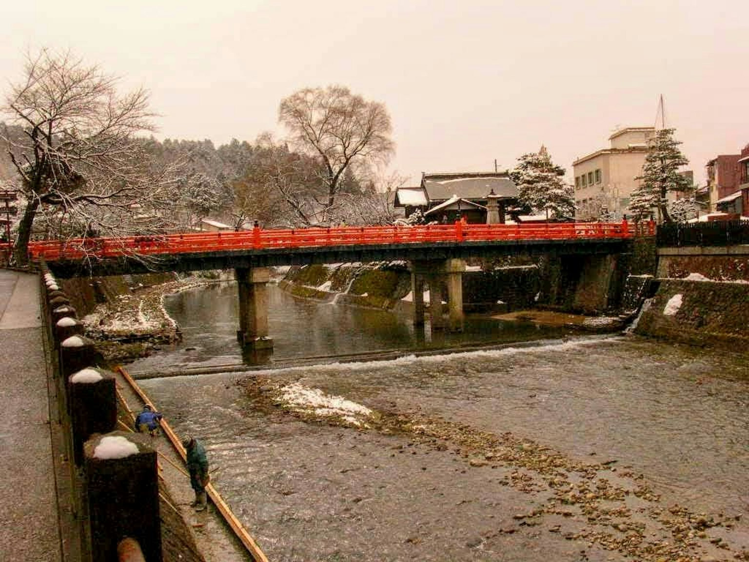 Fiume coperto di neve con un ponte rosso in inverno