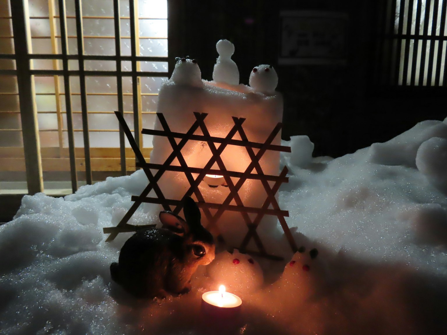 Ein Kaninchen neben einem Kerzenlicht umgeben von Schneeskulpturen