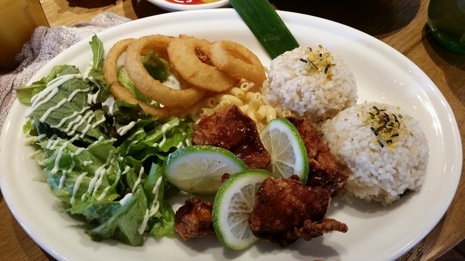 Ein köstlicher Teller mit Hähnchen, Reis, Salat, Zwiebelringen und Limettenscheiben