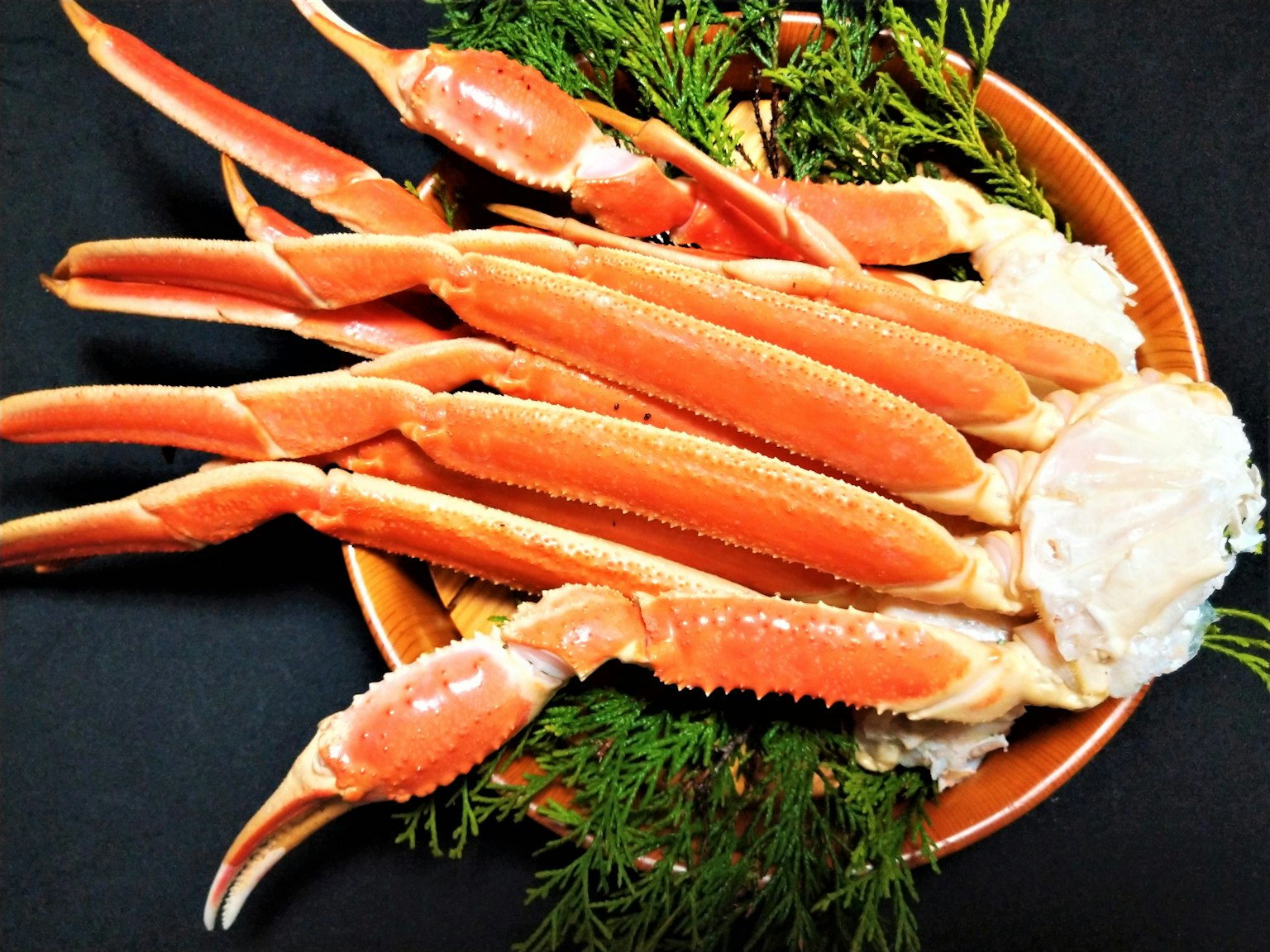 Fresh crab legs arranged on a plate with green garnish