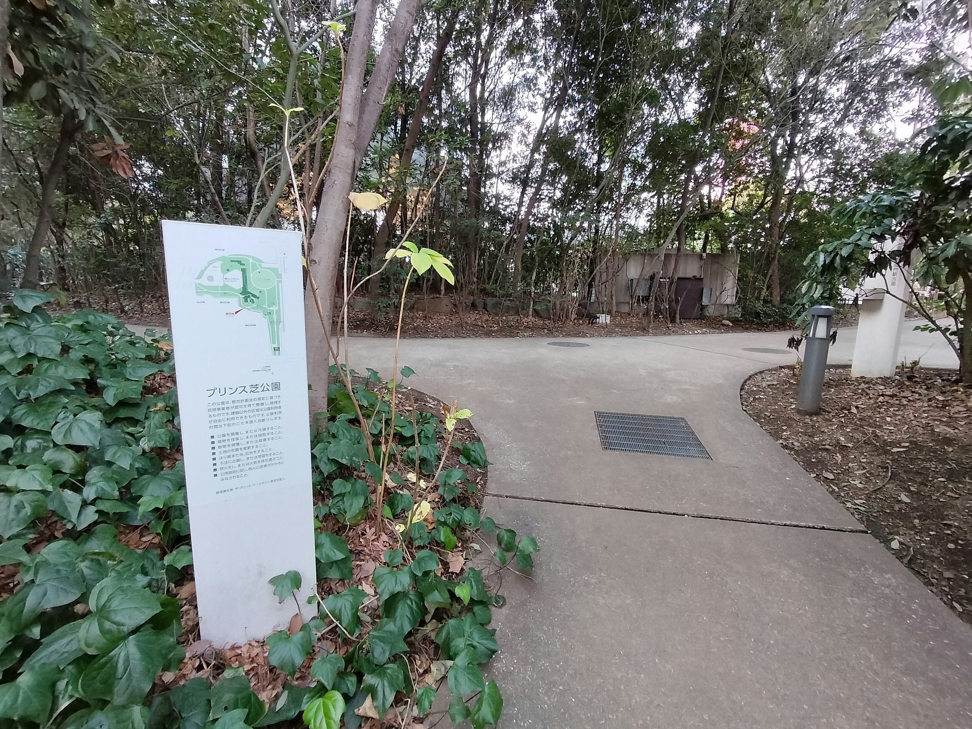 Sendero de jardín al aire libre con un cartel informativo rodeado de vegetación