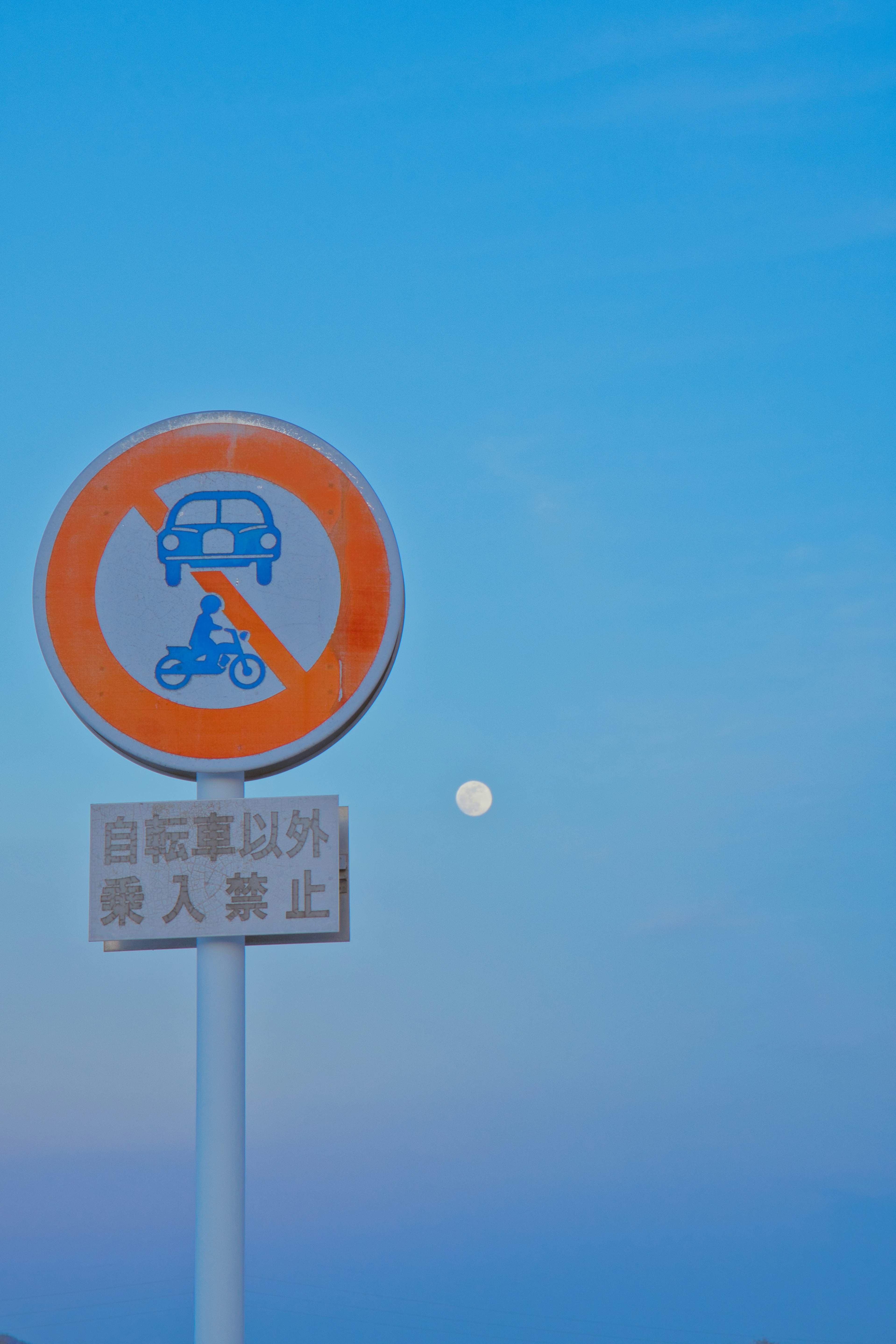 Señal de prohibición para bicicletas y peatones sobre un cielo azul con la luna