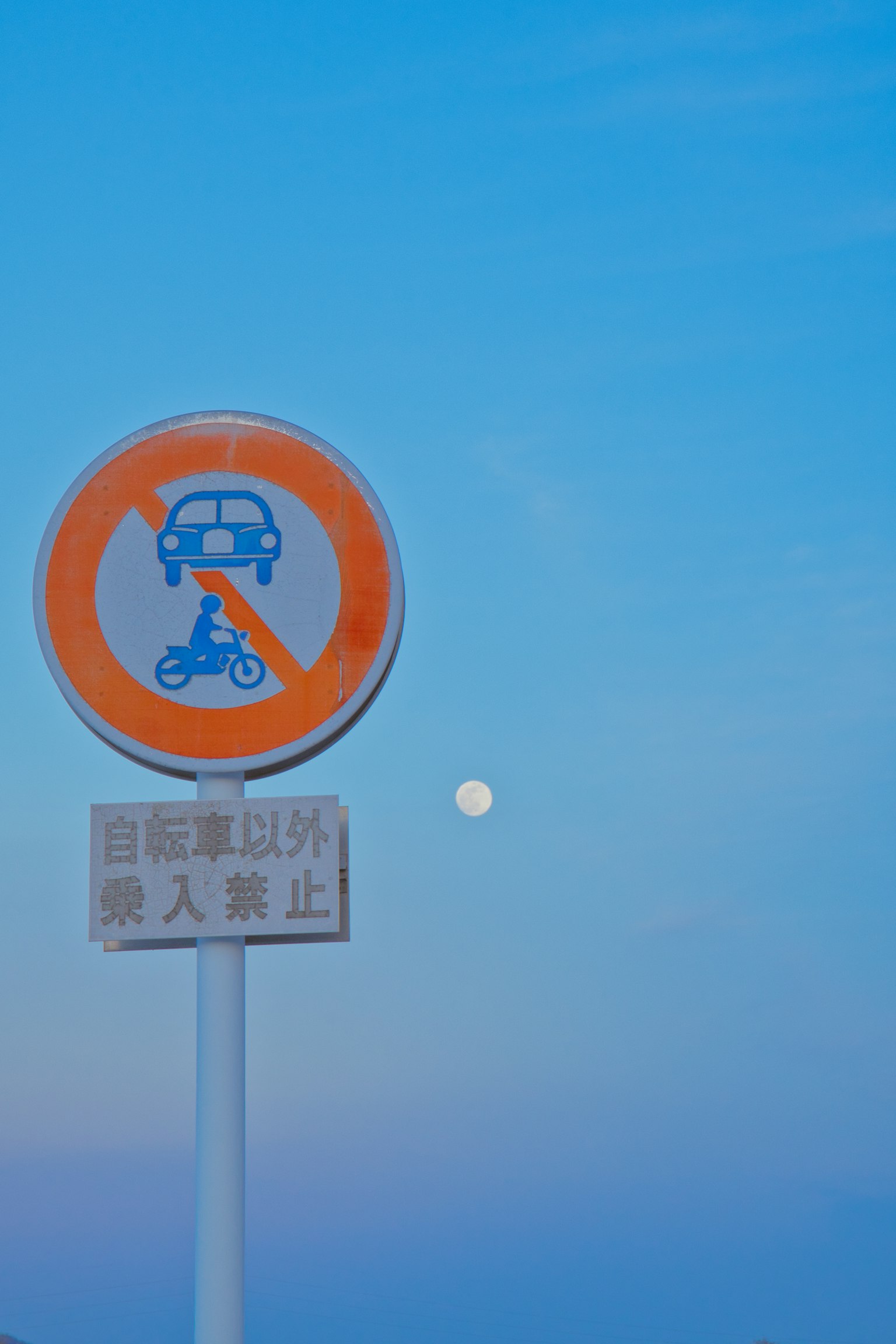 Parkverbotsschild vor einem blauen Himmel mit einem vollen Mond