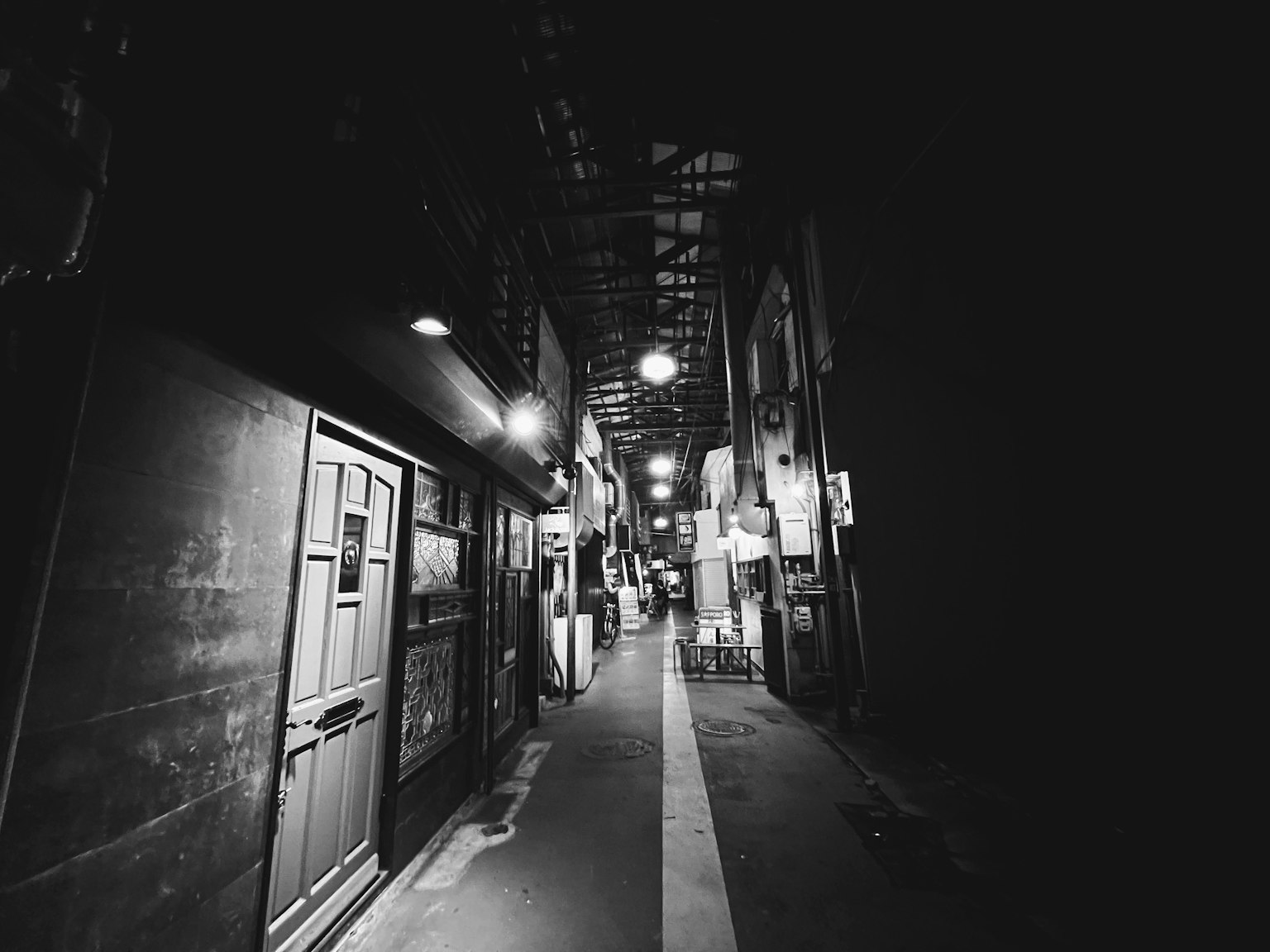 Callejón oscuro y estrecho con puertas y luces arriba