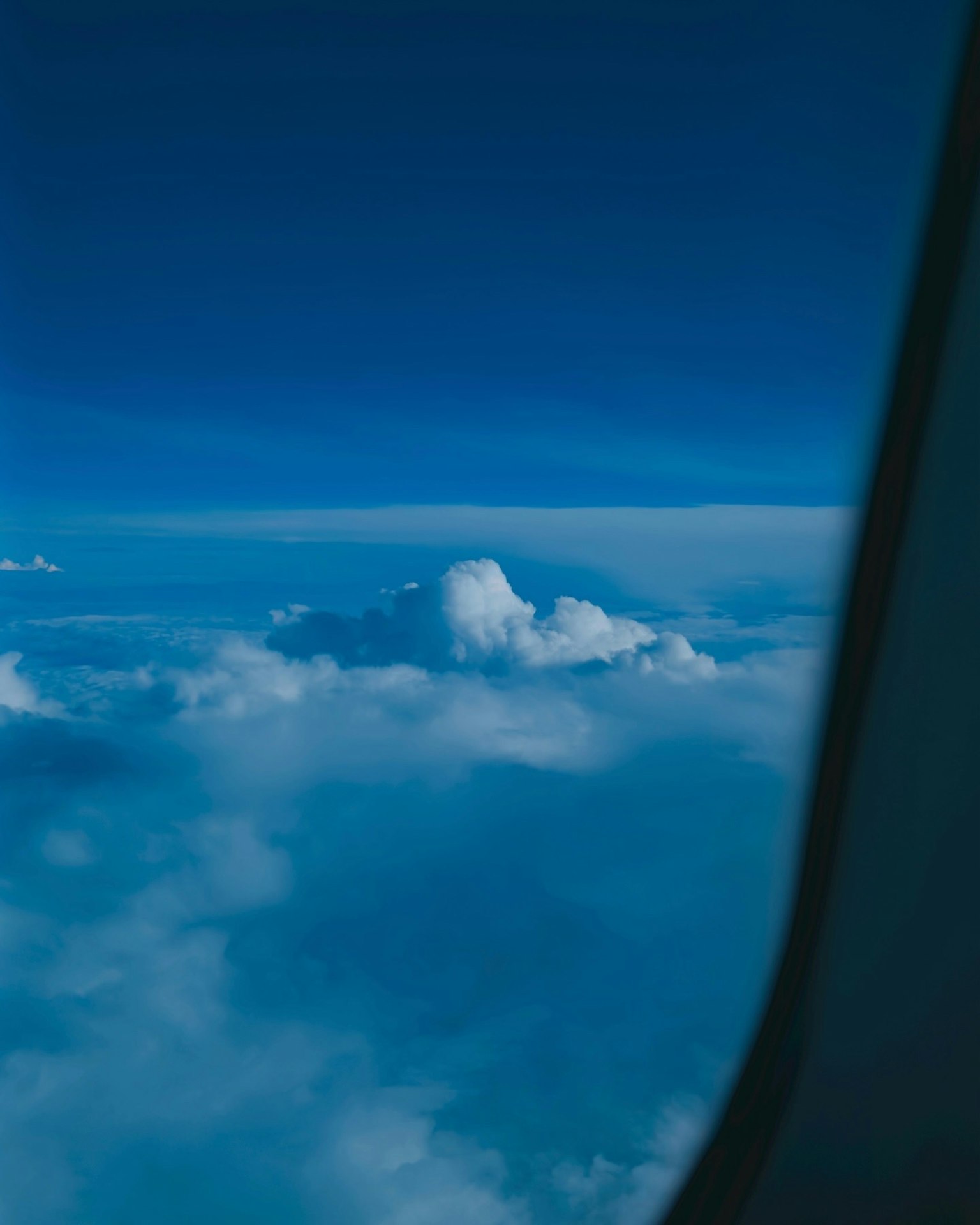 Una vista del cielo azul y las nubes con parte de una ventana visible