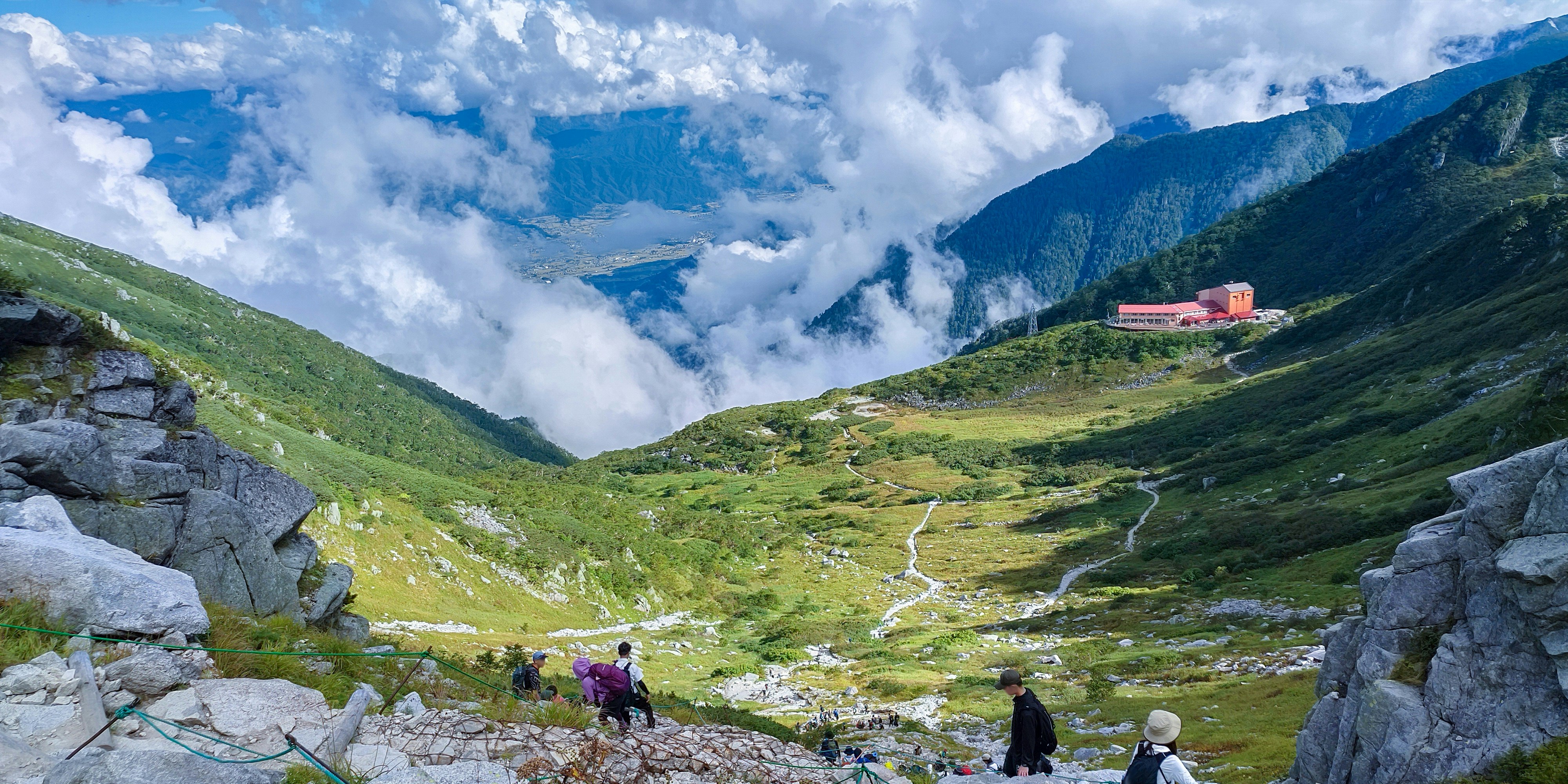宝剑岳与千畳敷卡尔的岩石步道上行走的登山者与多云天空