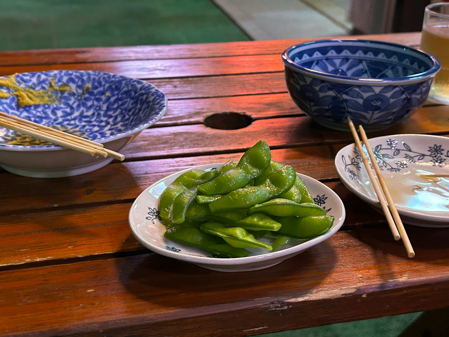Edamame served on a wooden table with various dishes