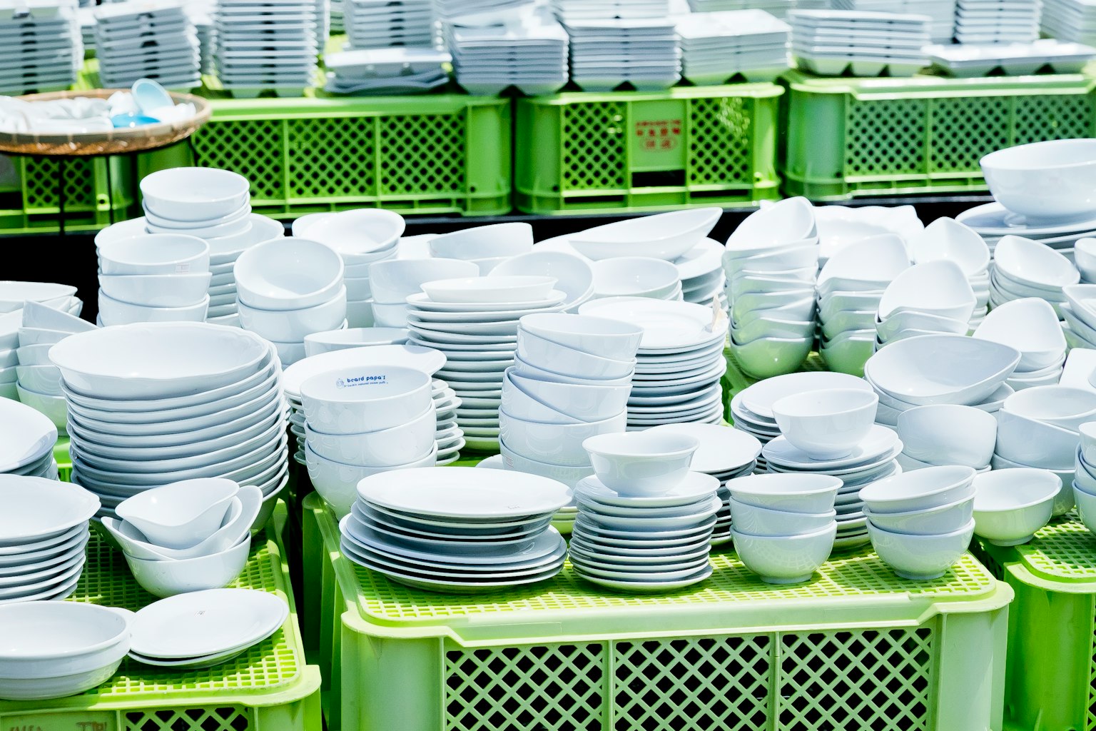Une collection d'assiettes et de bols blancs empilés sur des caisses vertes