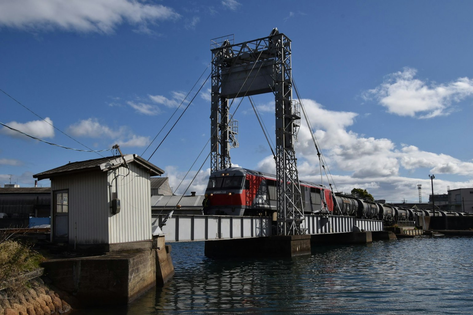 Train rouge traversant un pont sur l'eau Ciel bleu avec des nuages