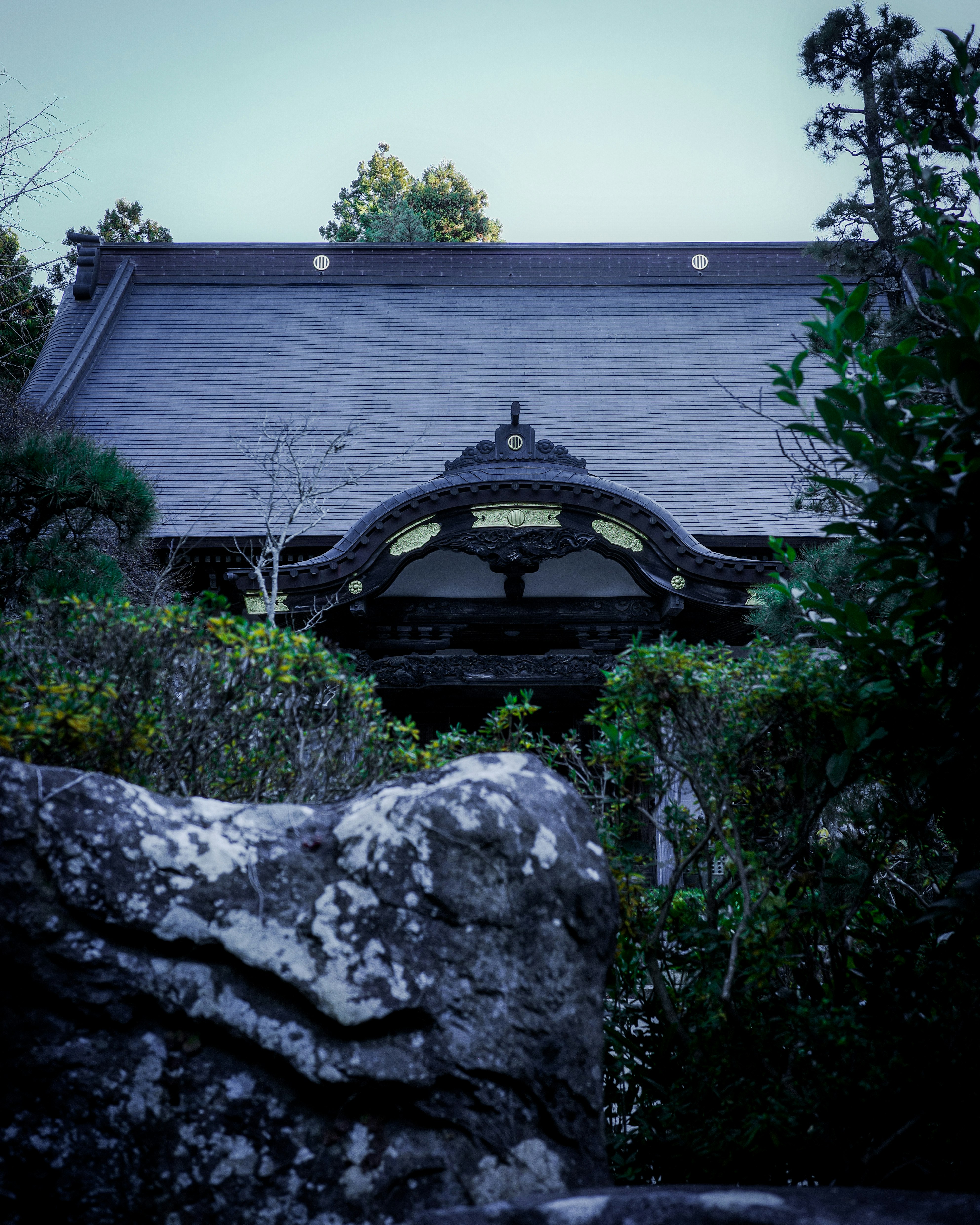 Japanese-style gate and roof in front of a stone garden