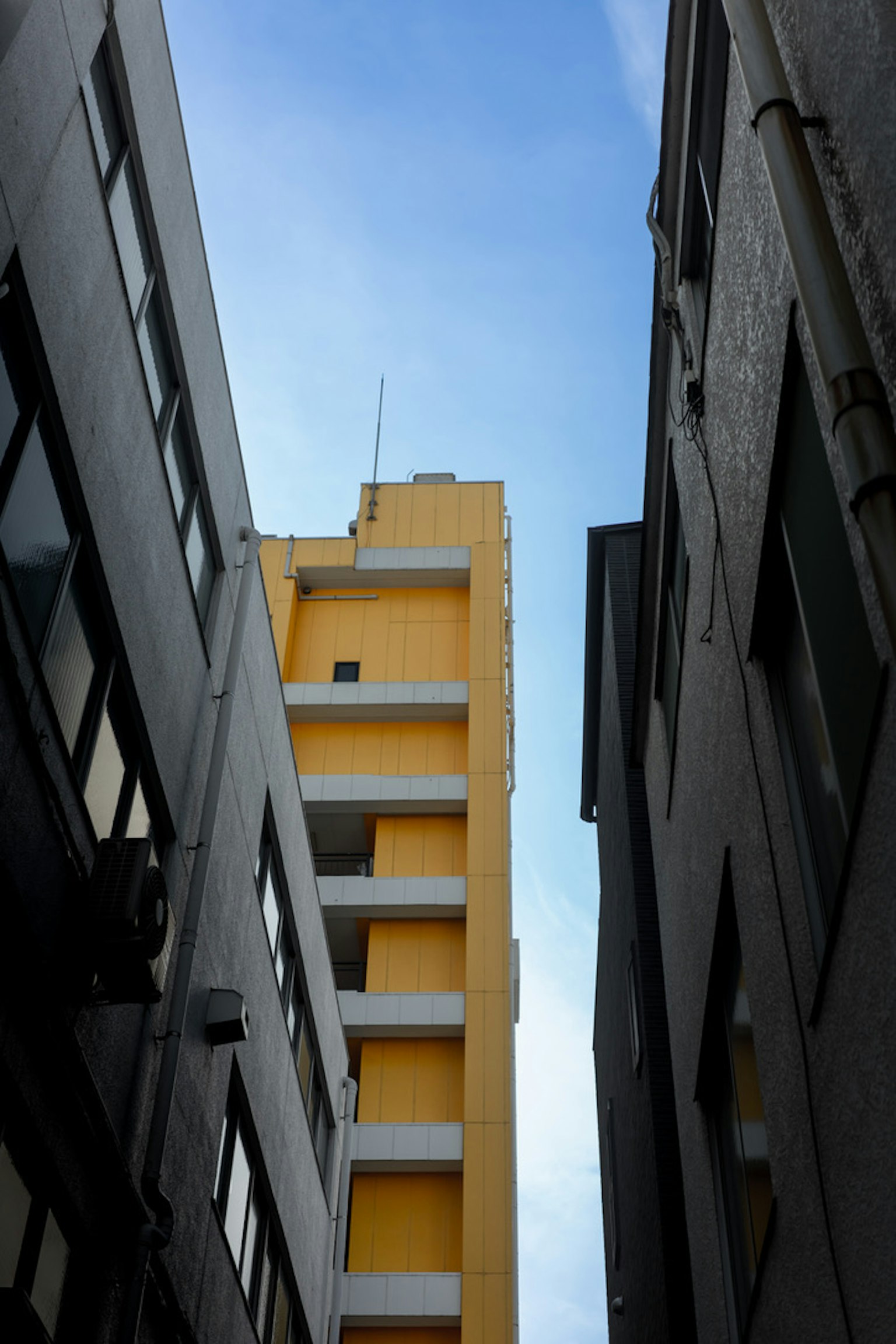 Yellow building visible between two gray buildings under a blue sky