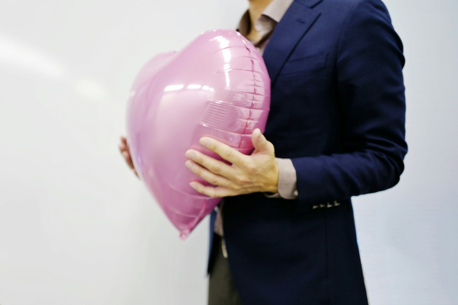 Pria memegang balon berbentuk hati berwarna pink