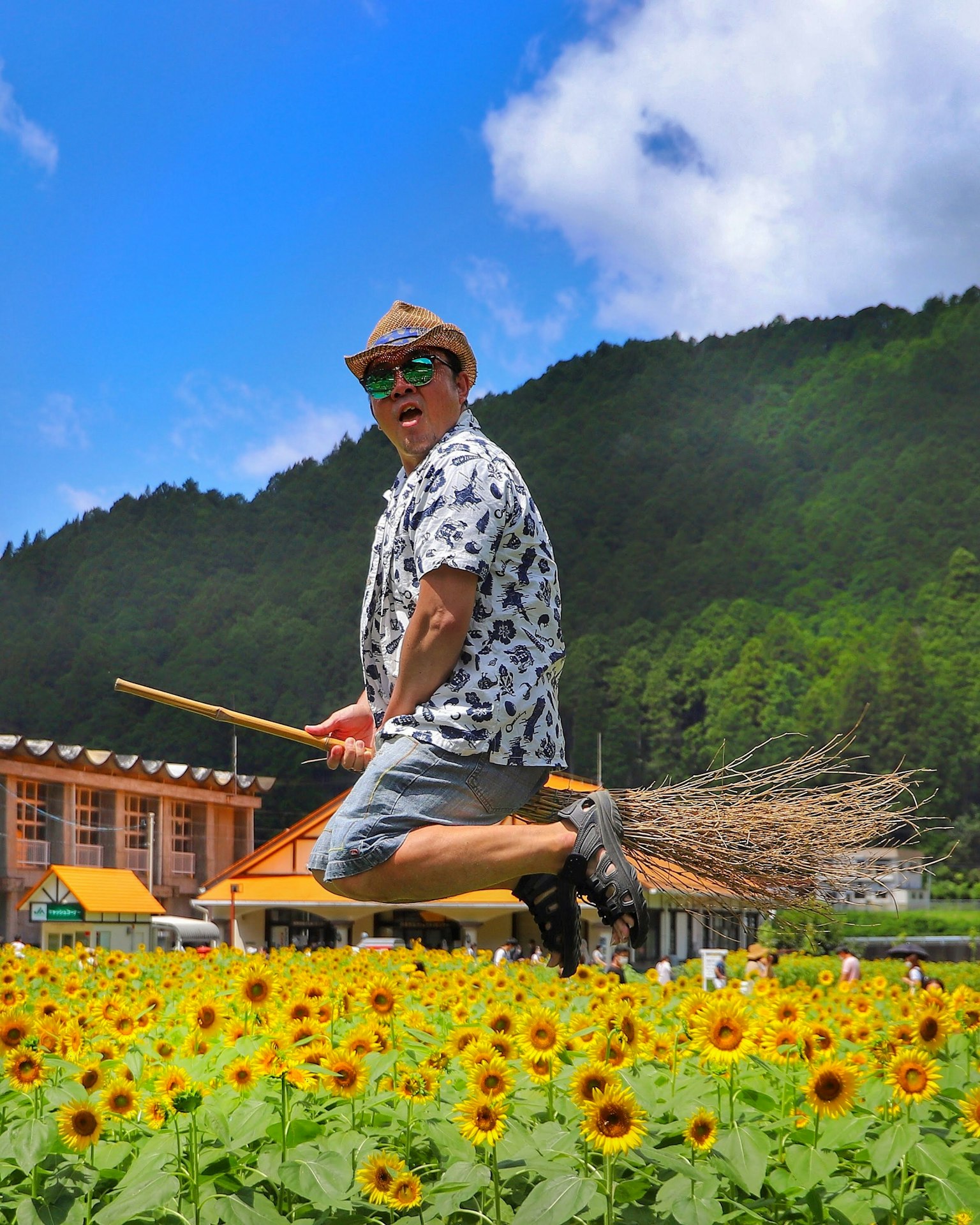 在向日葵田里跳跃的男人骑着扫帚