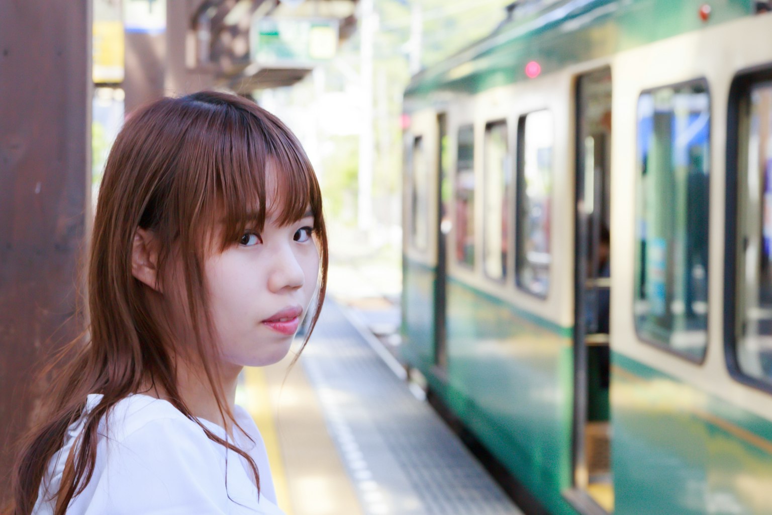 Woman waiting at the train platform with a green train