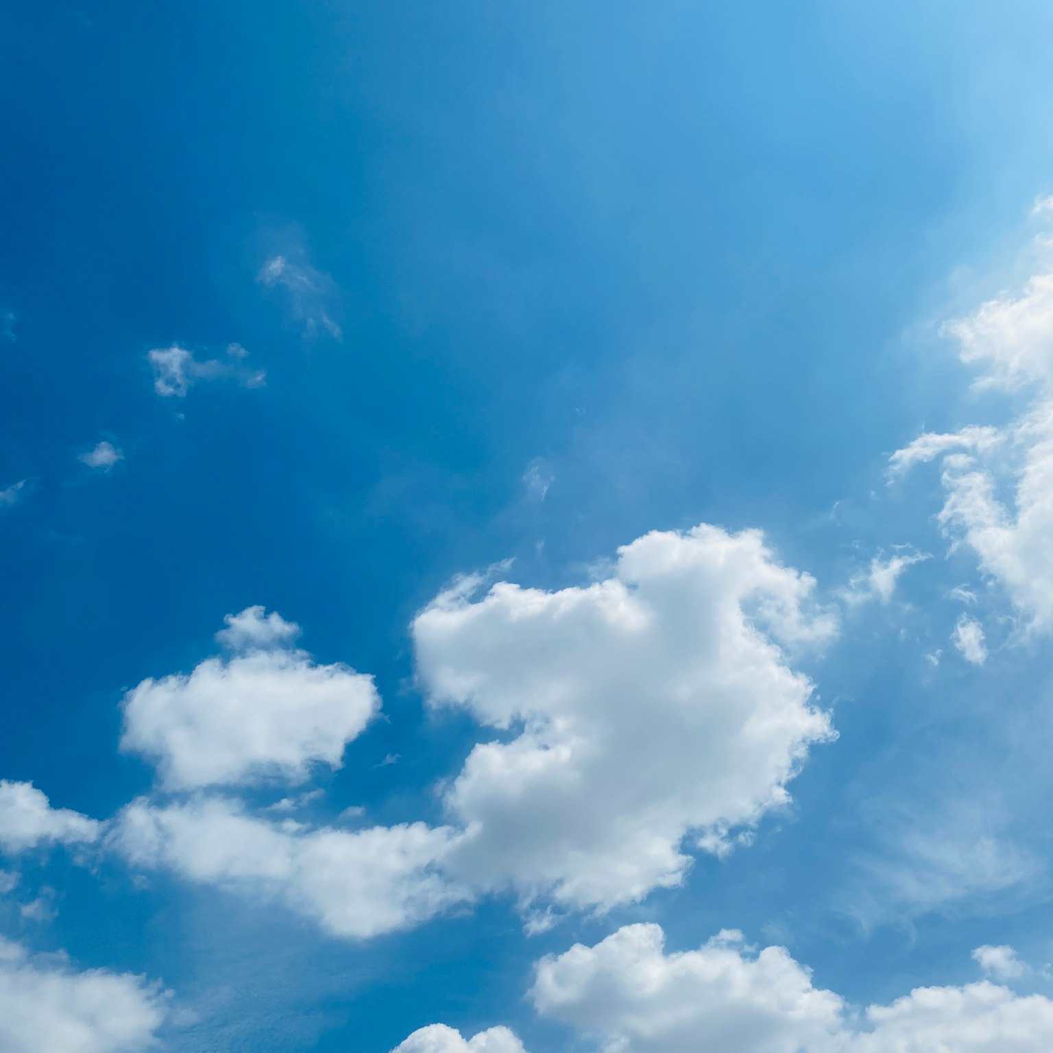 Ein klarer blauer Himmel mit flauschigen weißen Wolken