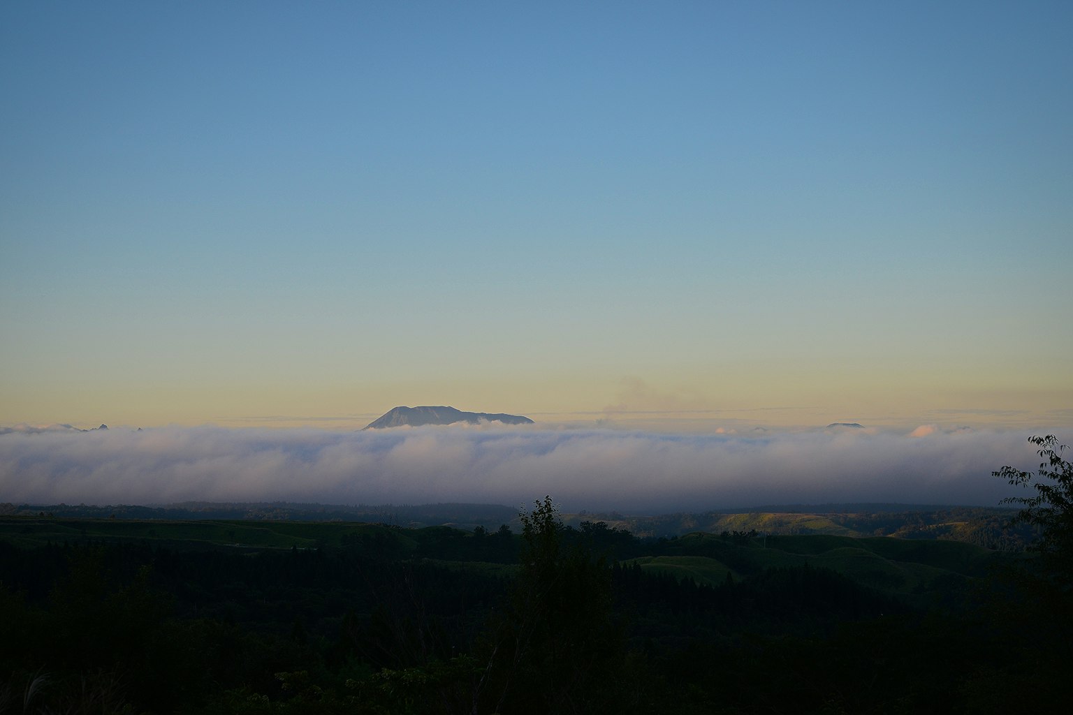 Paesaggio montano coperto da un mare di nuvole sotto un cielo blu