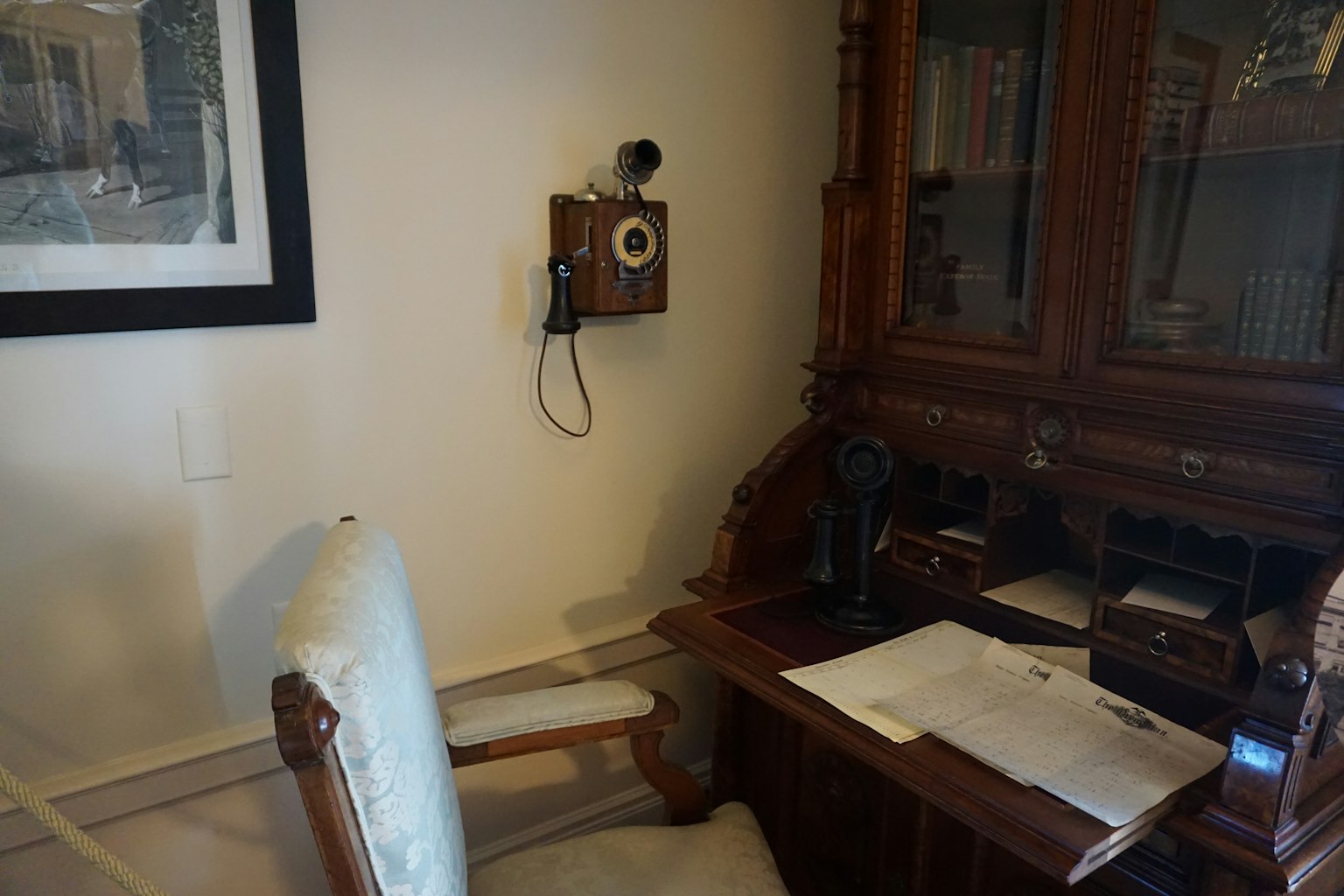 Angolo di una stanza con una scrivania in legno e una sedia con un telefono antico