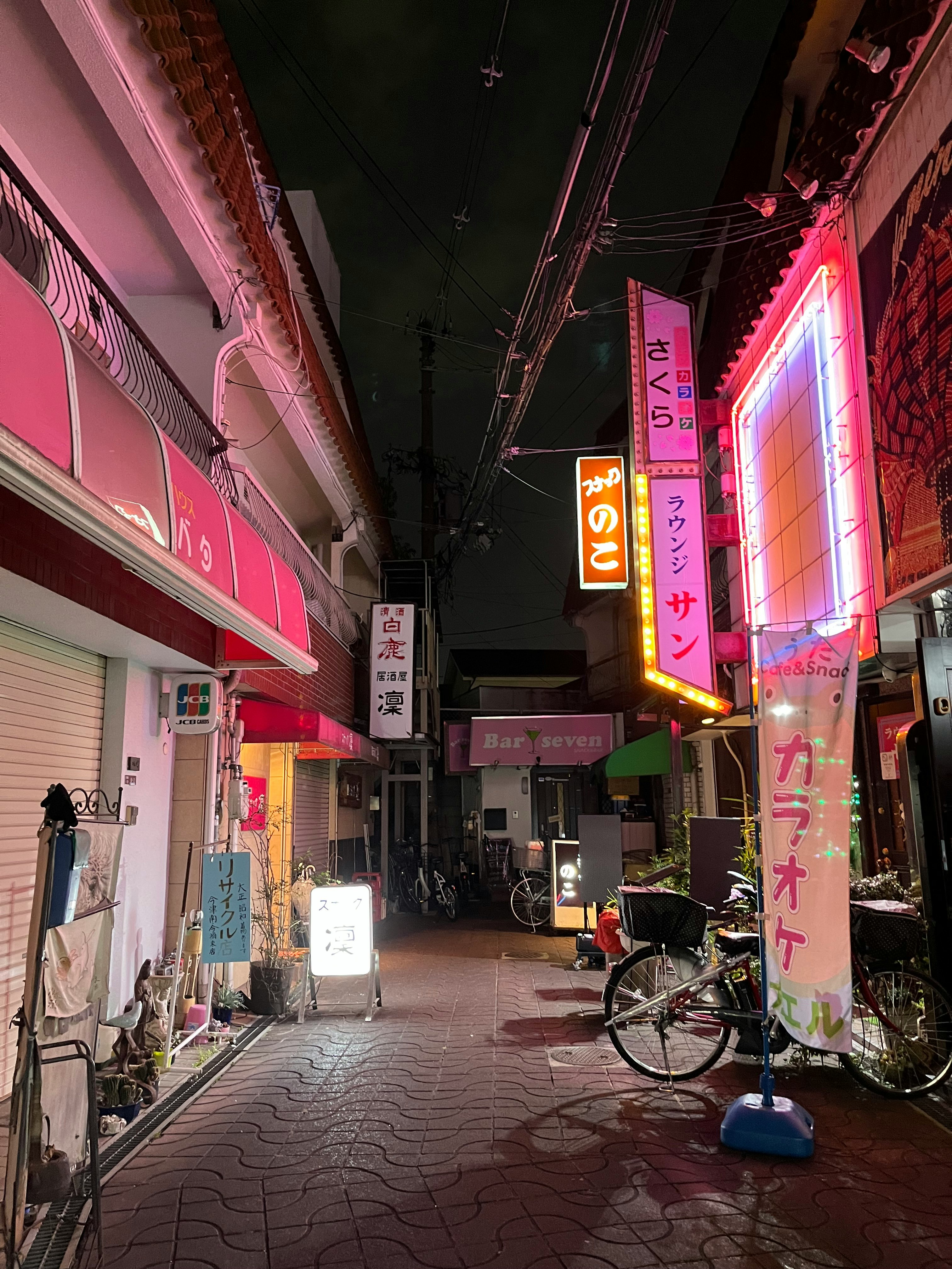 夜の路地に並ぶ看板と自転車のある商店街の通り