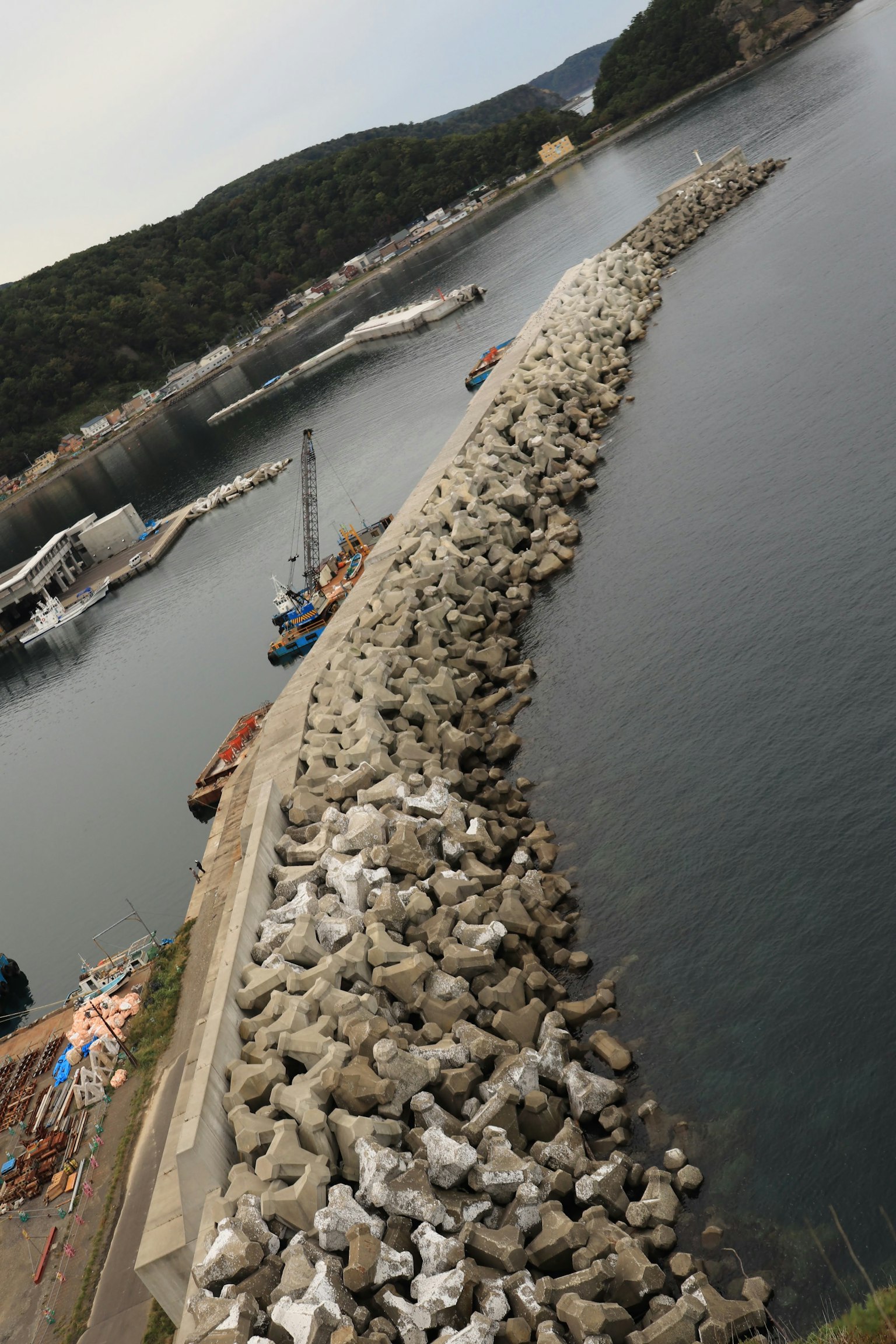 Un brise-lames en pierre s'étendant dans la mer avec des bateaux à proximité
