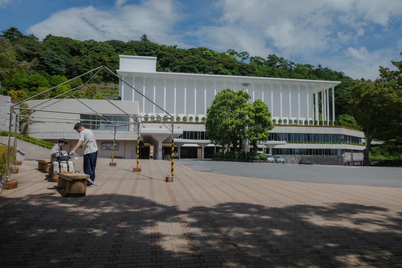 一座白色建筑和绿色树木以及在户外工作的人