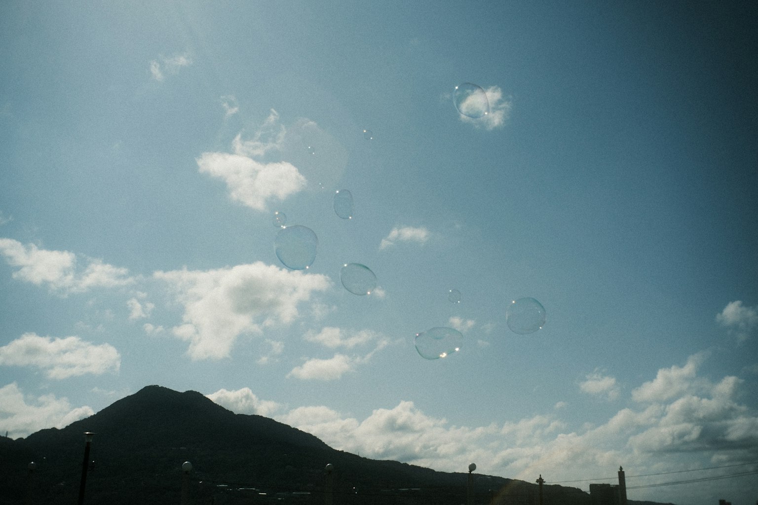 Bubbles floating in a blue sky with a mountain silhouette