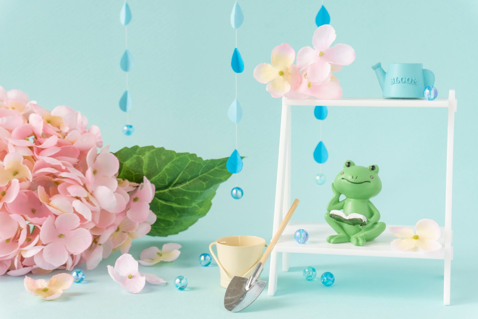 Một bức tượng ếch xanh được bao quanh bởi hoa hồng trên nền xanh
