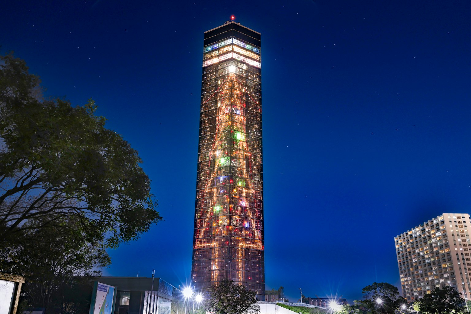Luces coloridas decoran un edificio alto contra el cielo nocturno