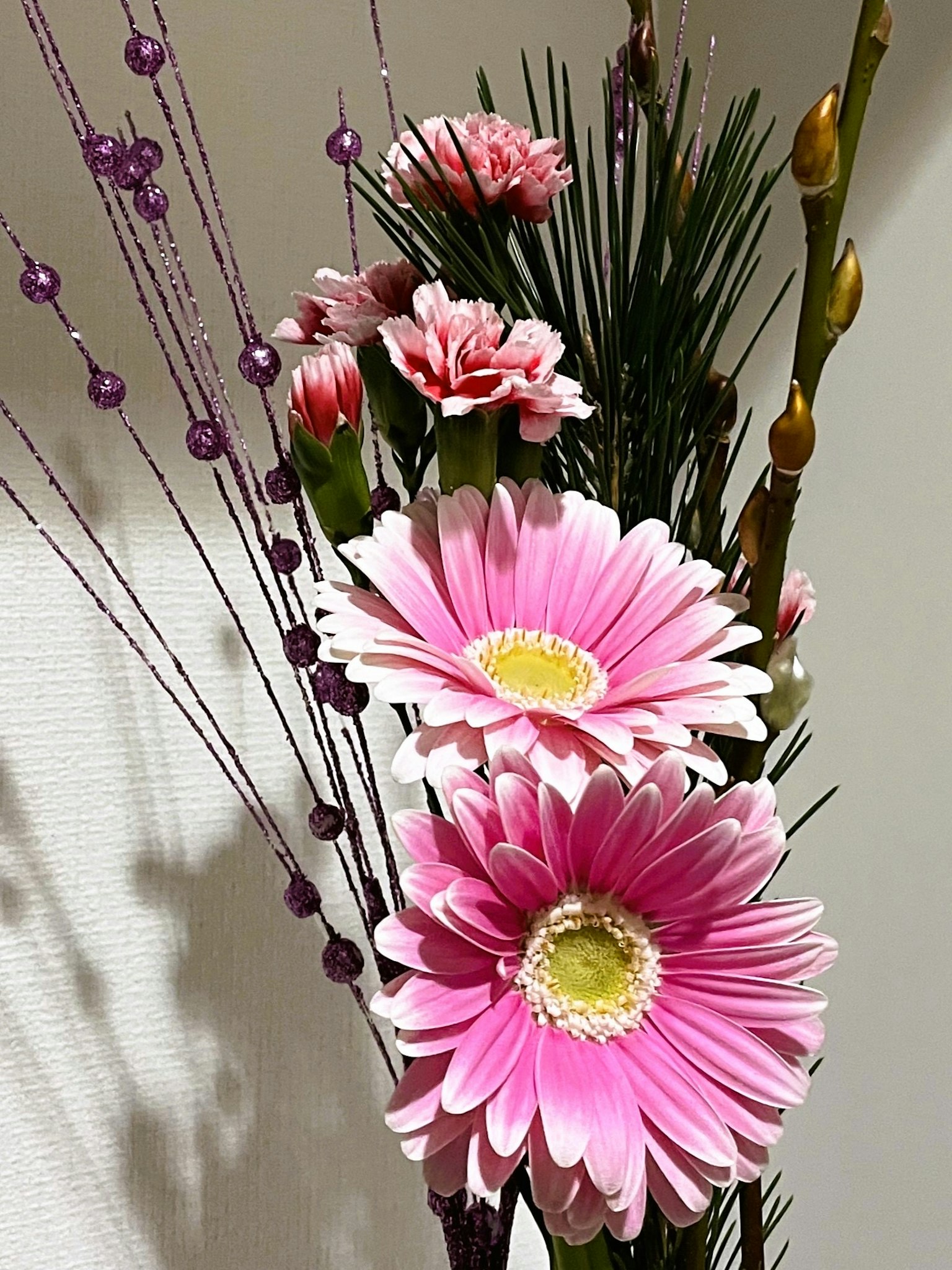 Arreglo floral con margaritas gerbera rosas y claveles con hojas verdes y cuentas moradas