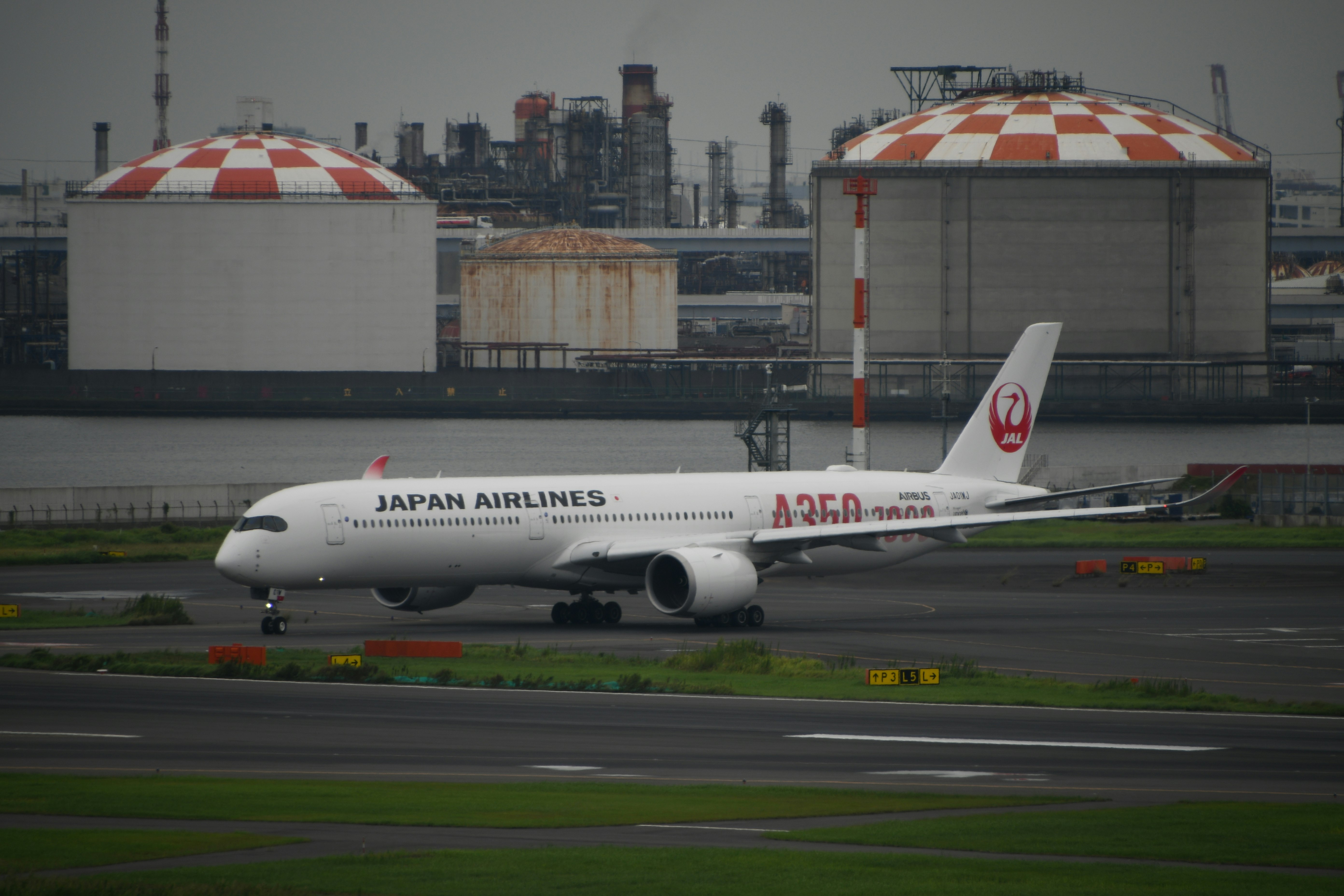 滑走路を走る日本航空の旅客機と空港施設の風景
