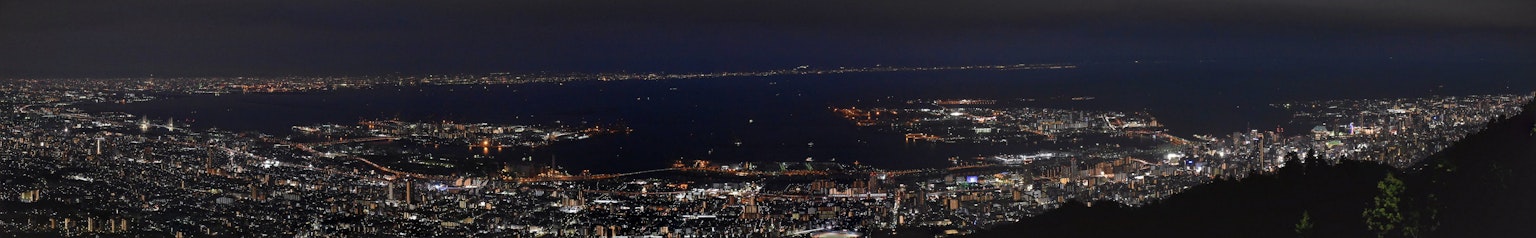 Panoramic night view of a city with bright lights and ocean