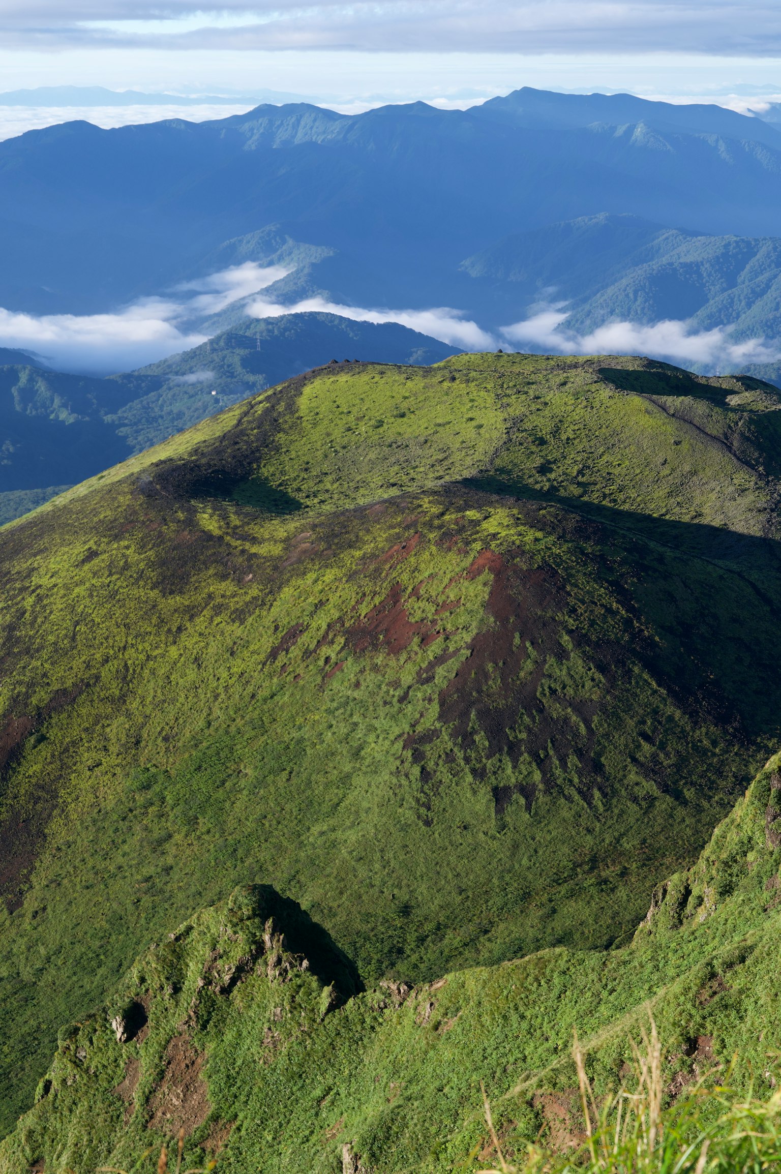Montañas verdes con un mar de nubes al fondo