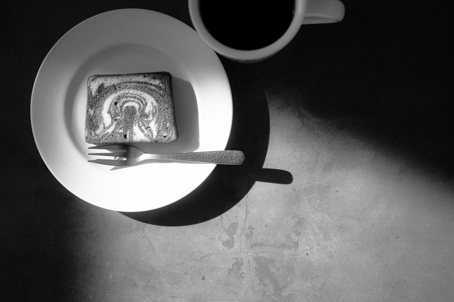 Immagine in bianco e nero di una tazza di caffè e un dessert su un piatto