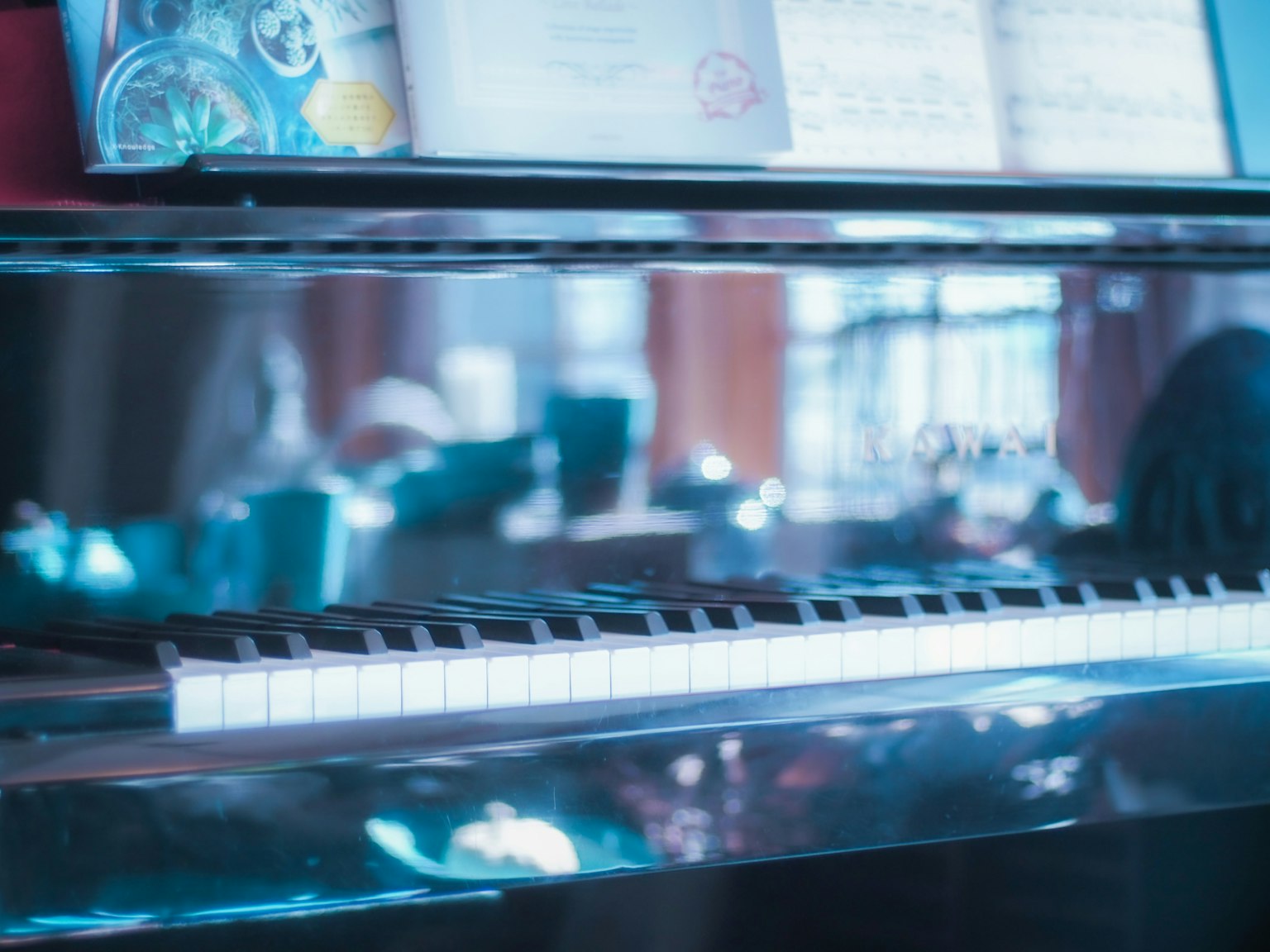 Tasti di pianoforte che riflettono una luce blu con spartiti