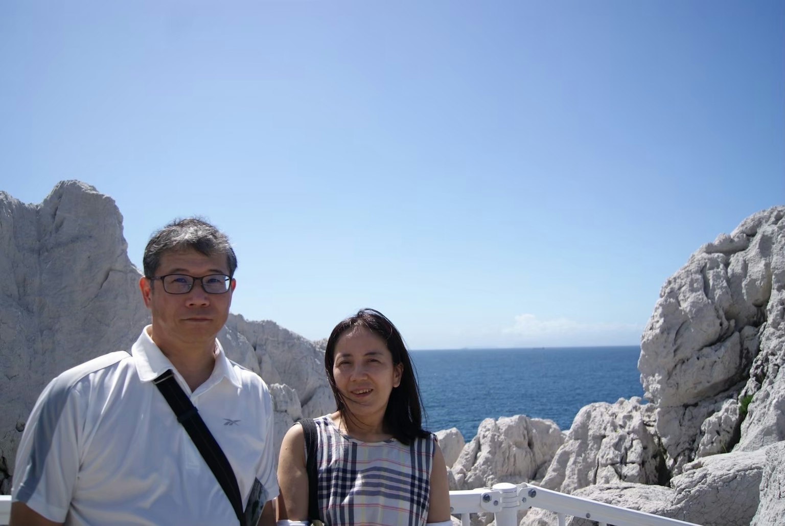 Two people standing between rocks with the ocean in the background