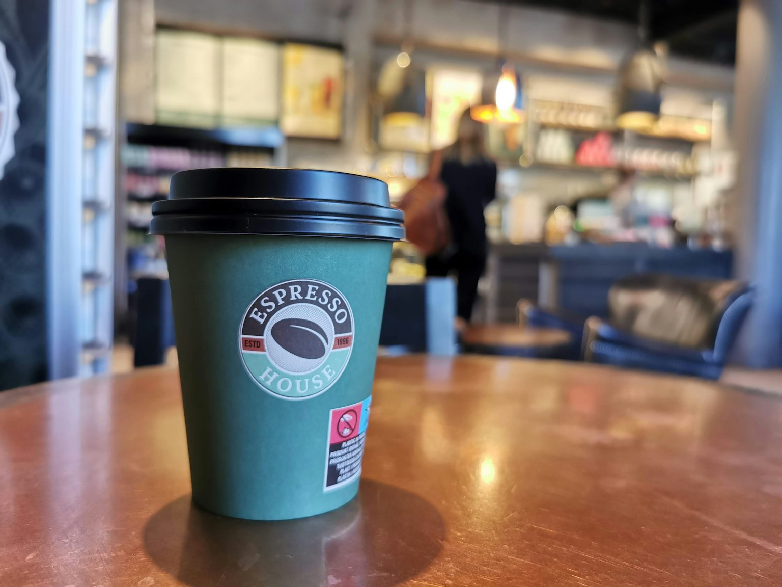 Cốc cà phê xanh Espresso House trên bàn trong quán cà phê