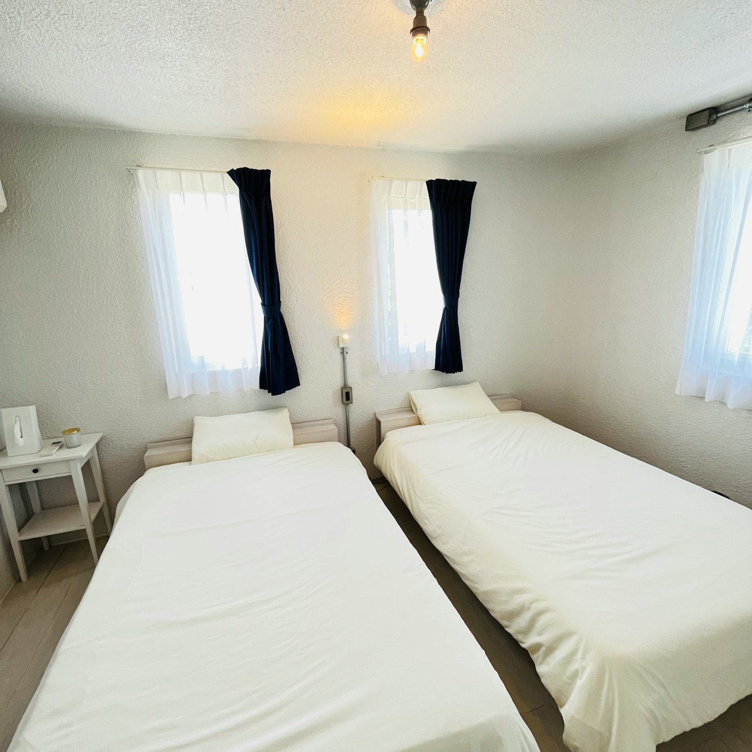 Bright room with two beds dressed in white sheets natural light streaming through windows