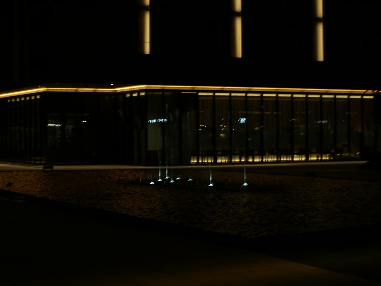 Illuminated glass building at night with surrounding lights