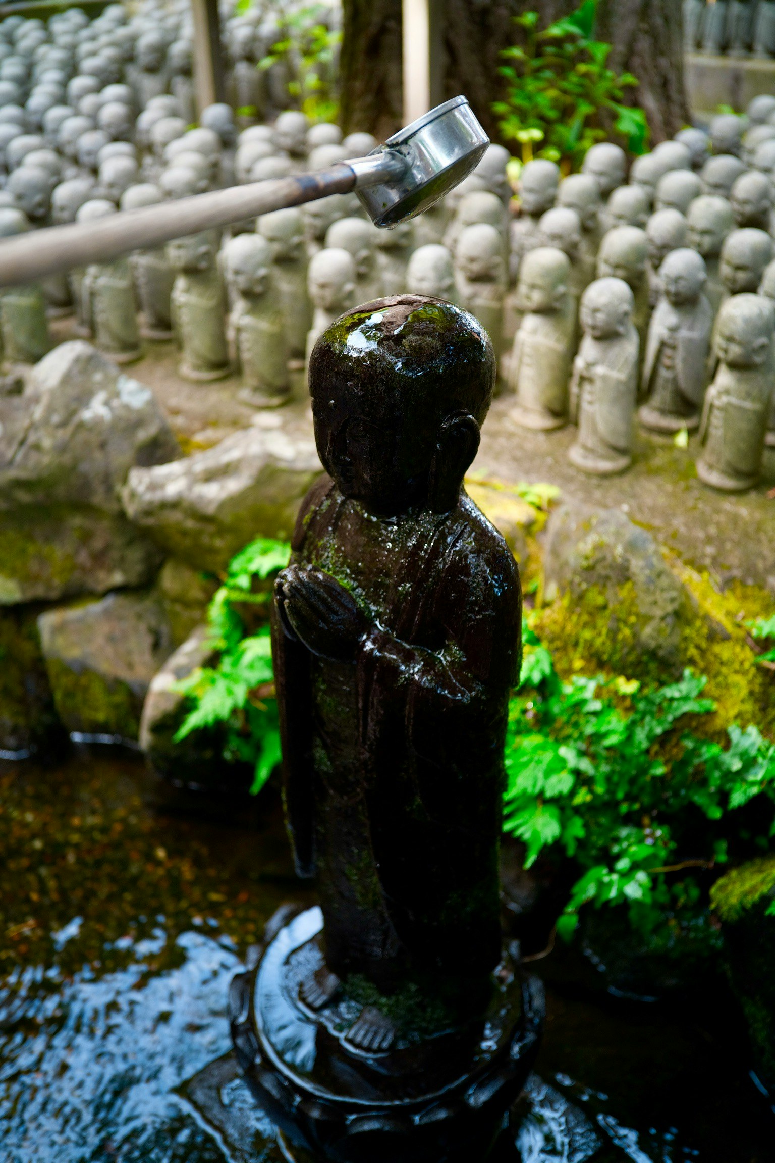 鎌倉の石仏と水の流れる小さな庭の風景