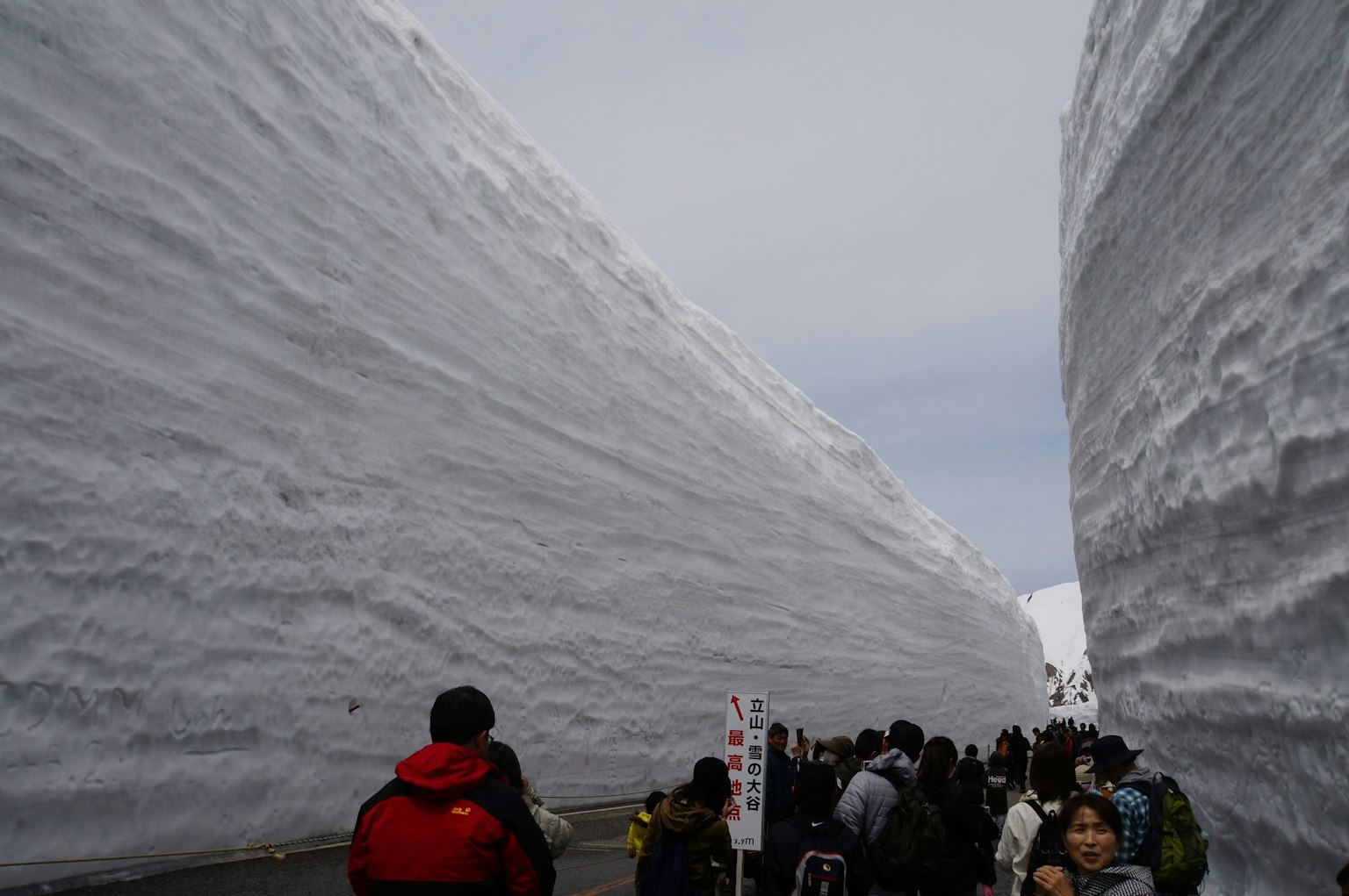Turisti che camminano tra alti muri di neve