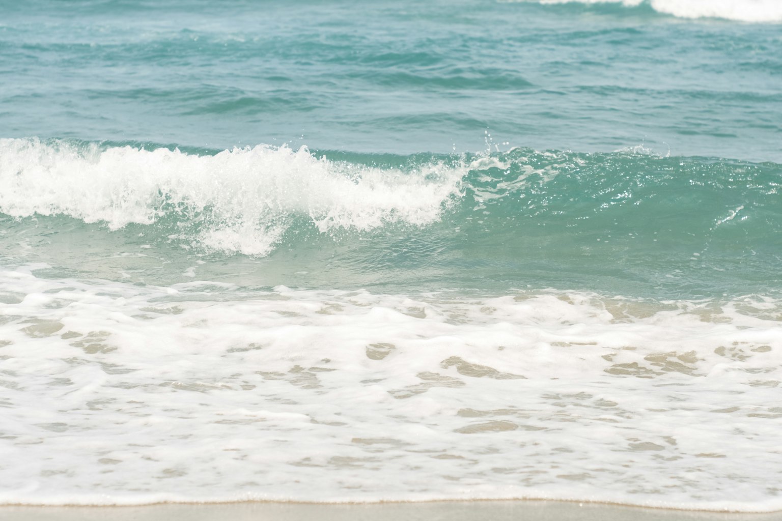 Sanfte Wellen des Ozeans, die an einen Sandstrand schlagen