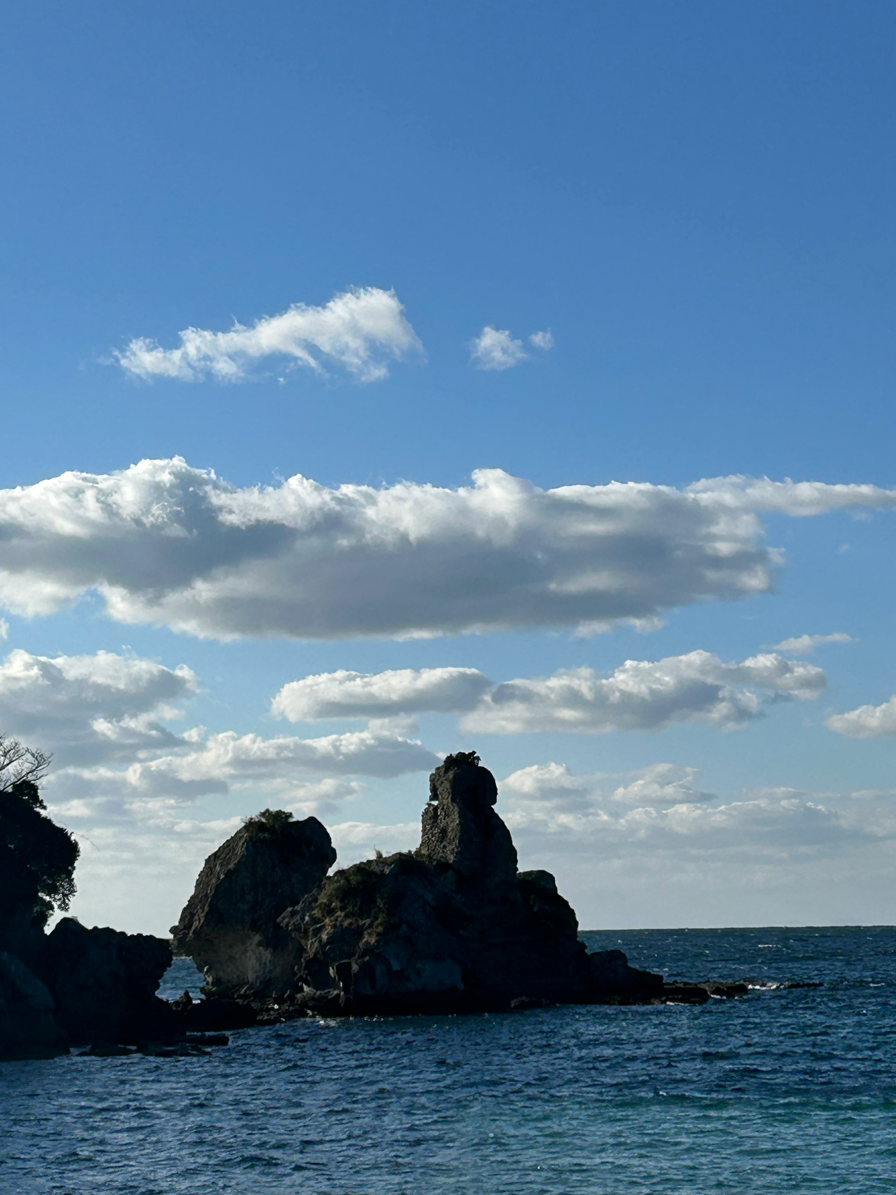海に浮かぶ岩と青空の下の海岸風景